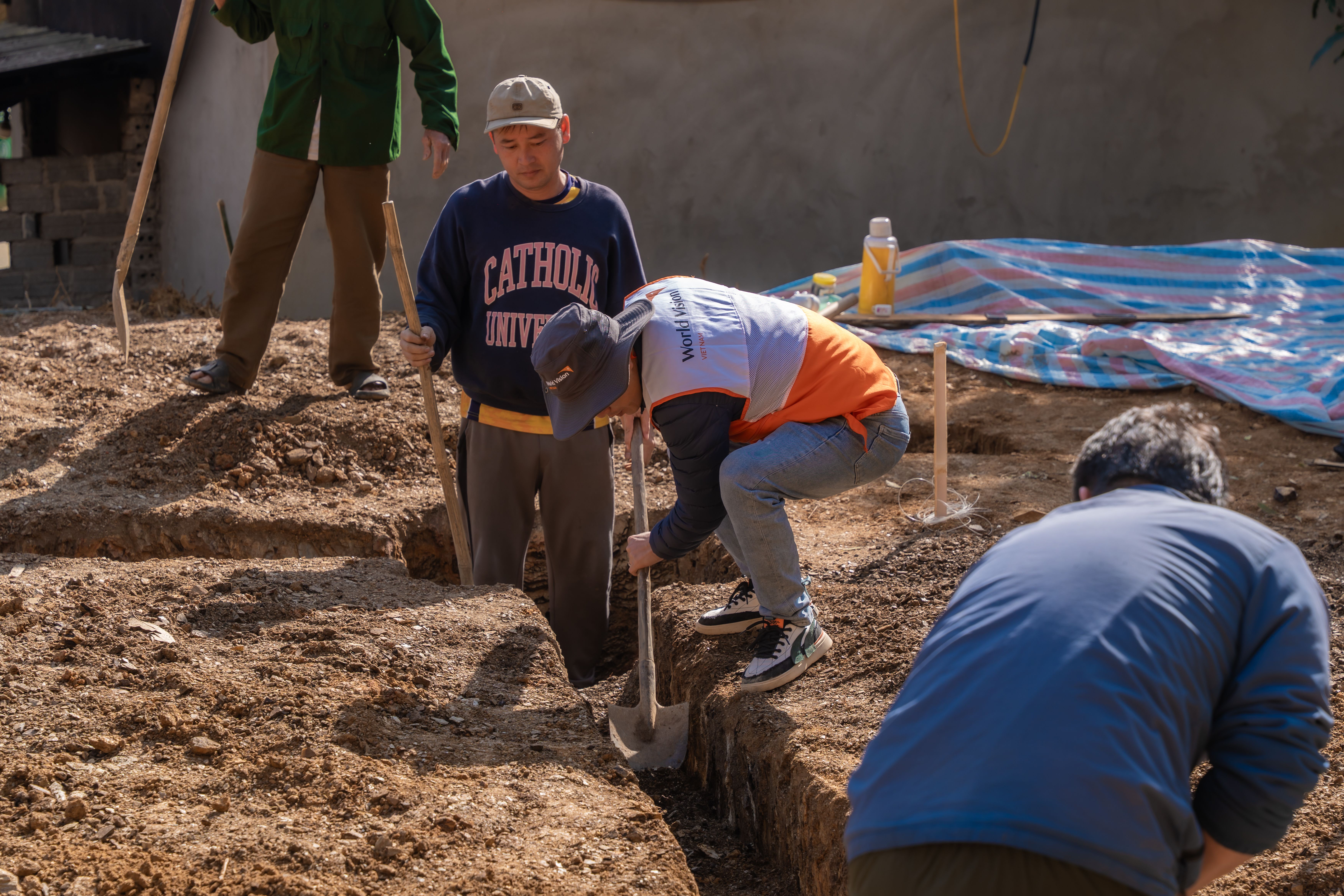 Perforated pipe being installed in a gravel trench beside foundation footing for subsurface drainage in San Antonio Texa