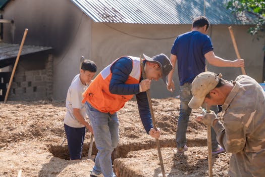 Group of workers digging foundation trenches at a construction site outdoors.