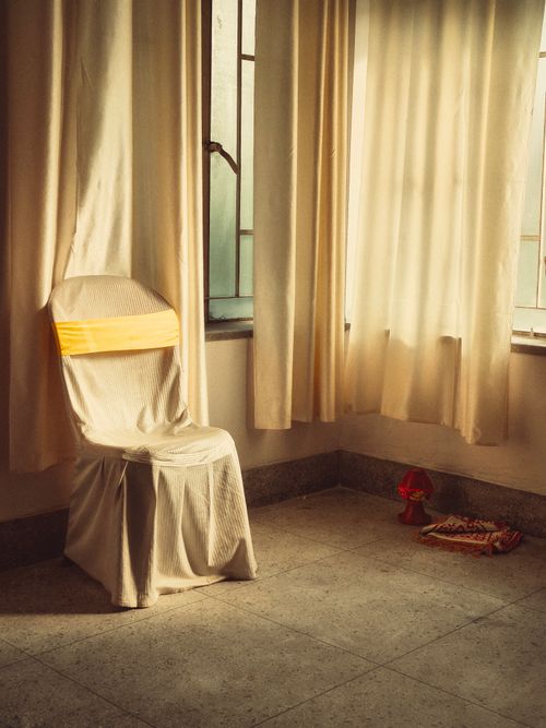 Free A cozy sunlit room in Kolkata featuring a covered chair and warm decor. Stock Photo