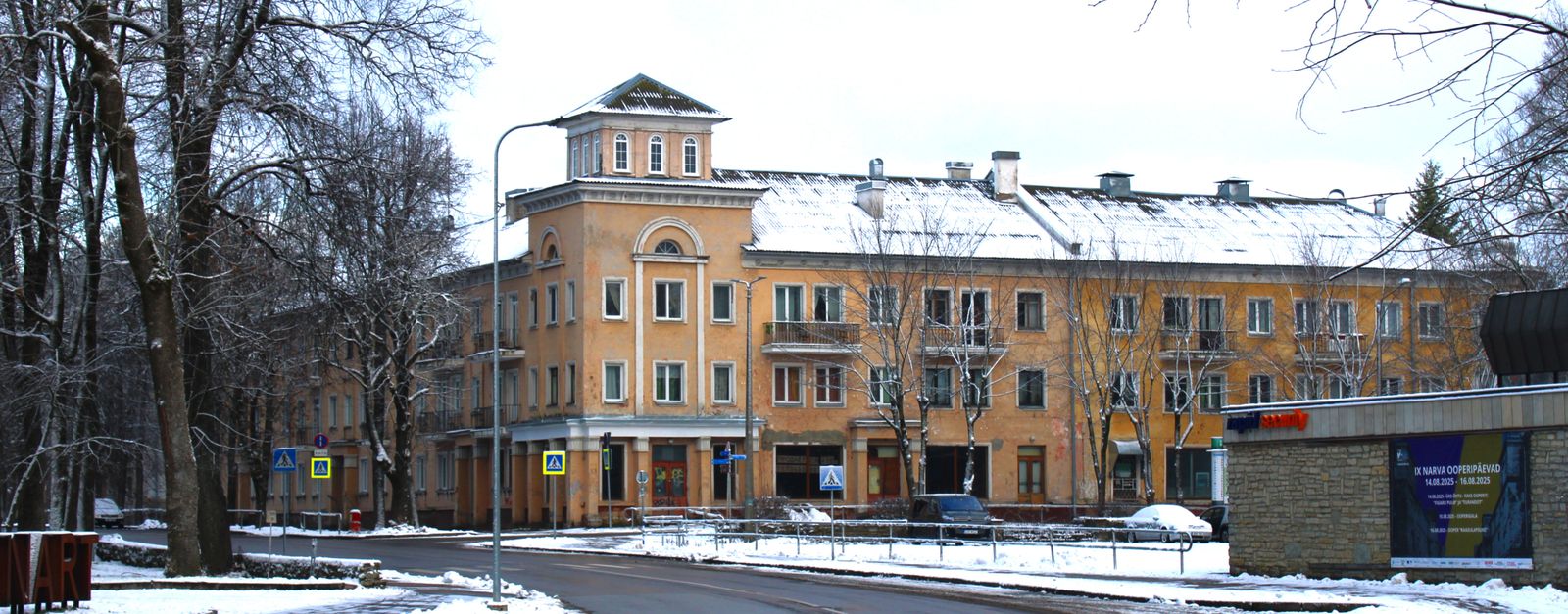 Snow-covered street in Narva, Estonia, featuring historic buildings and urban winter scenery.