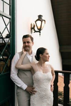 Couple in wedding dress and suit posing by a lamppost, with warm, elegant lighting.