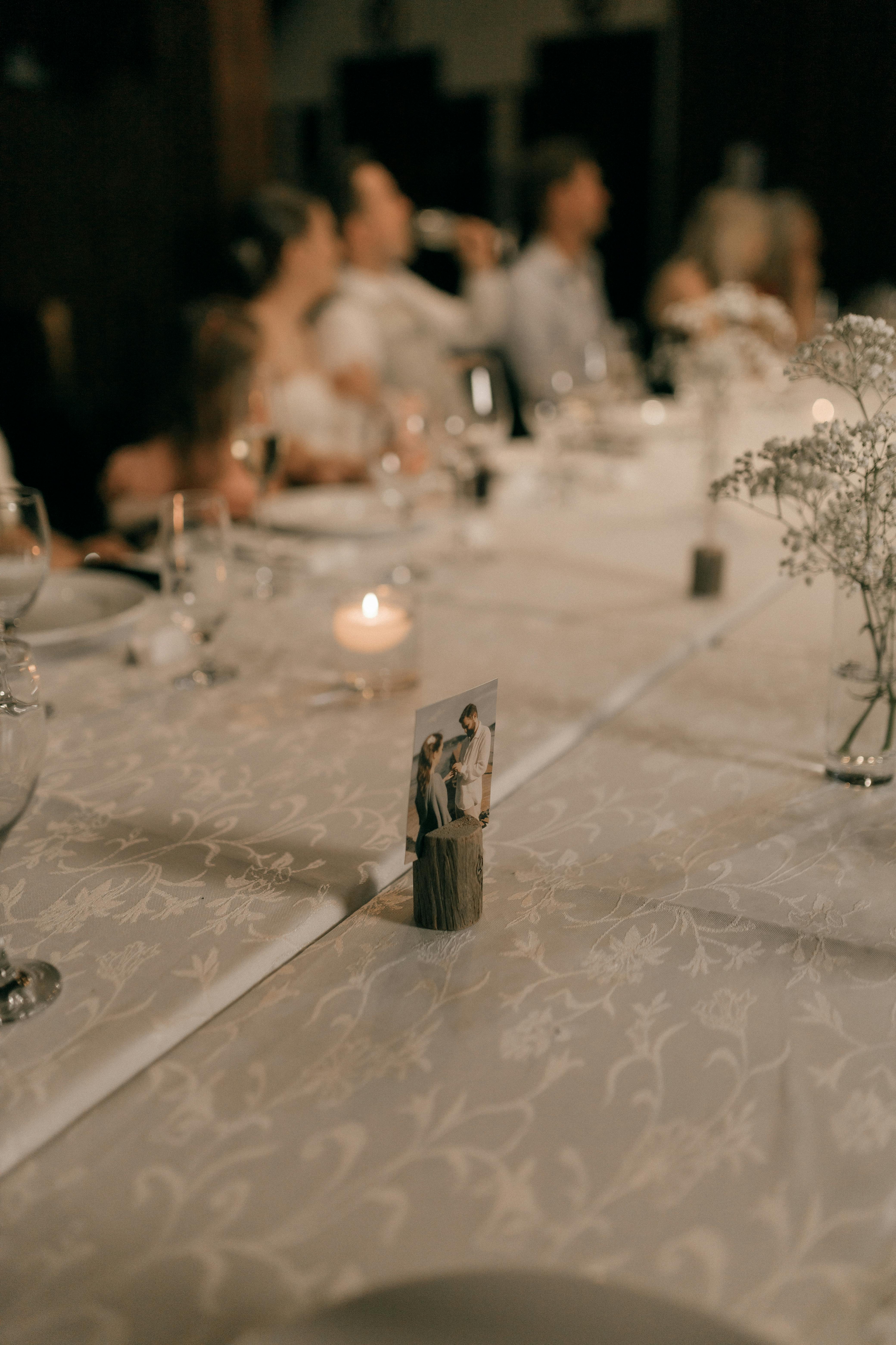 A beautifully arranged wedding reception table with candles and guests.