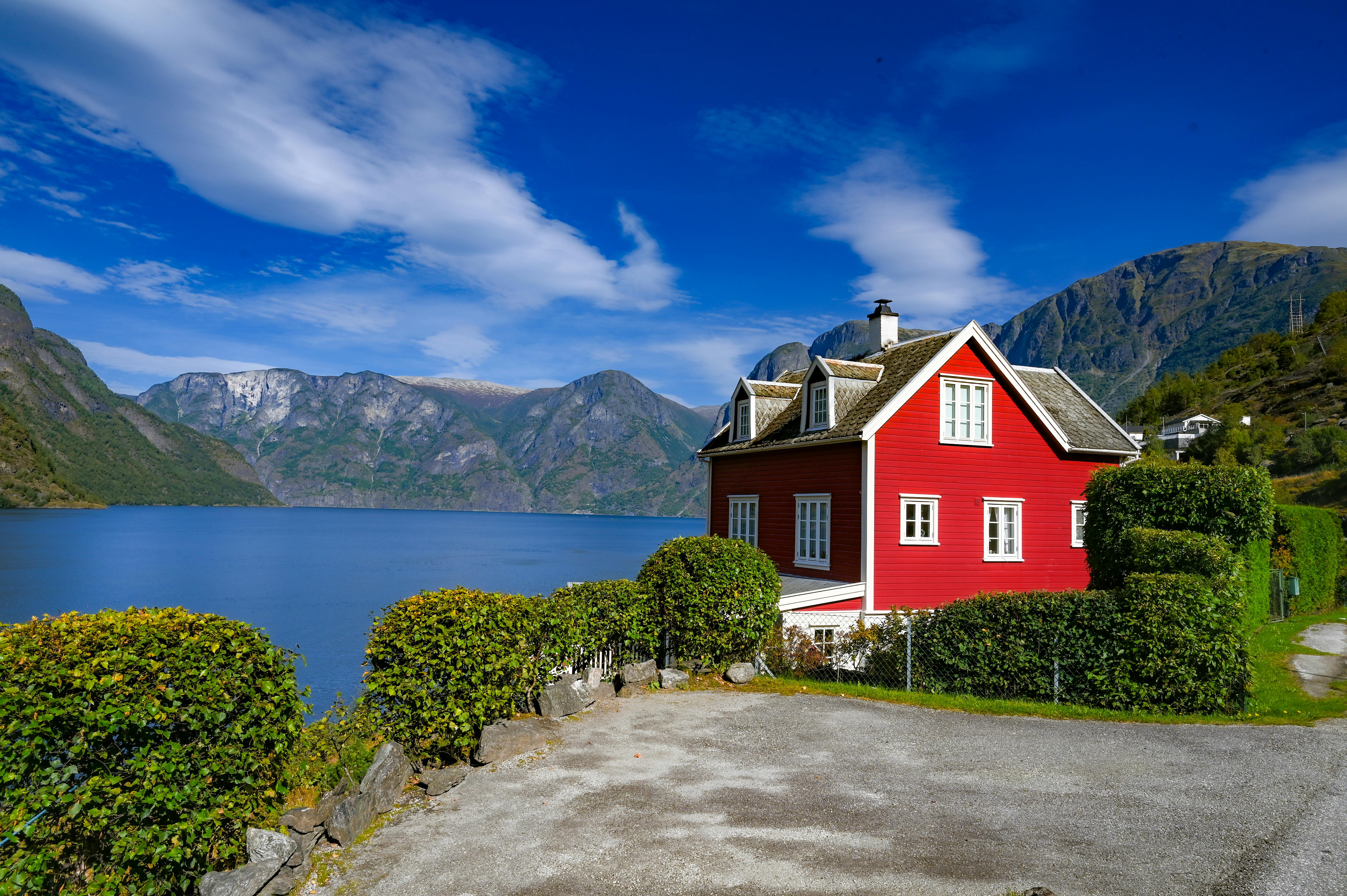 Une maison rouge pittoresque au bord d'un magnifique fjord norvégien, entourée de montagnes.
