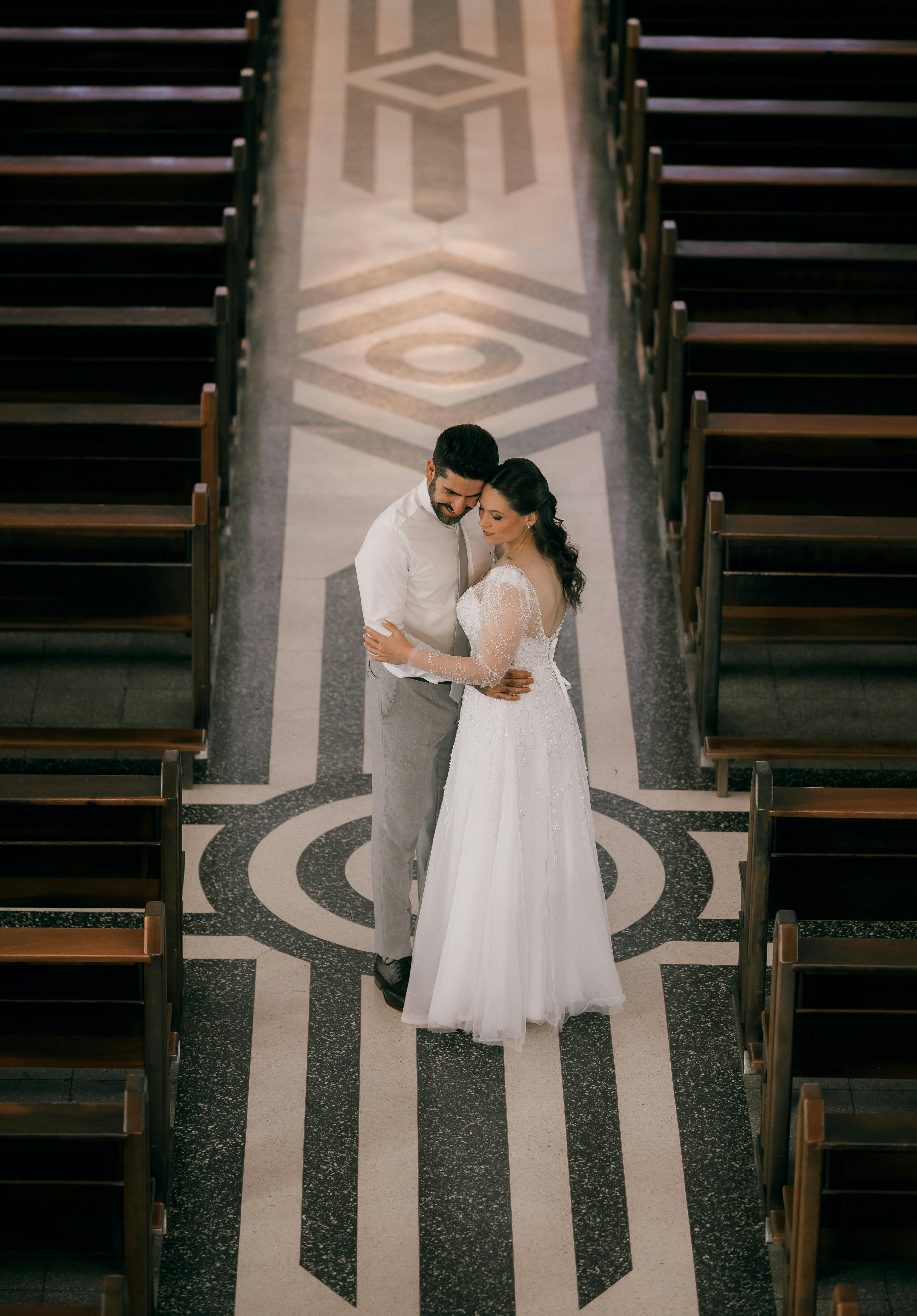 Bride and groom sharing a romantic dance in a beautifully decorated church aisle.