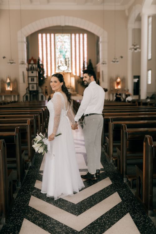 Free Bride and groom holding hands in a beautifully decorated church aisle. Stock Photo