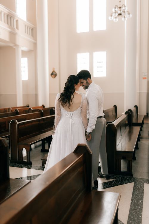Free Bride and groom share an intimate moment in a beautifully lit church interior. Stock Photo