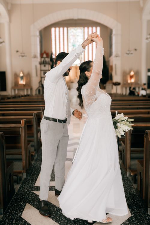 Free Bride and groom share a joyful dance inside a beautifully decorated church aisle. Stock Photo