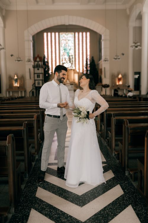 Free Bride and groom joyfully share a moment in an elegantly decorated church ceremony. Stock Photo