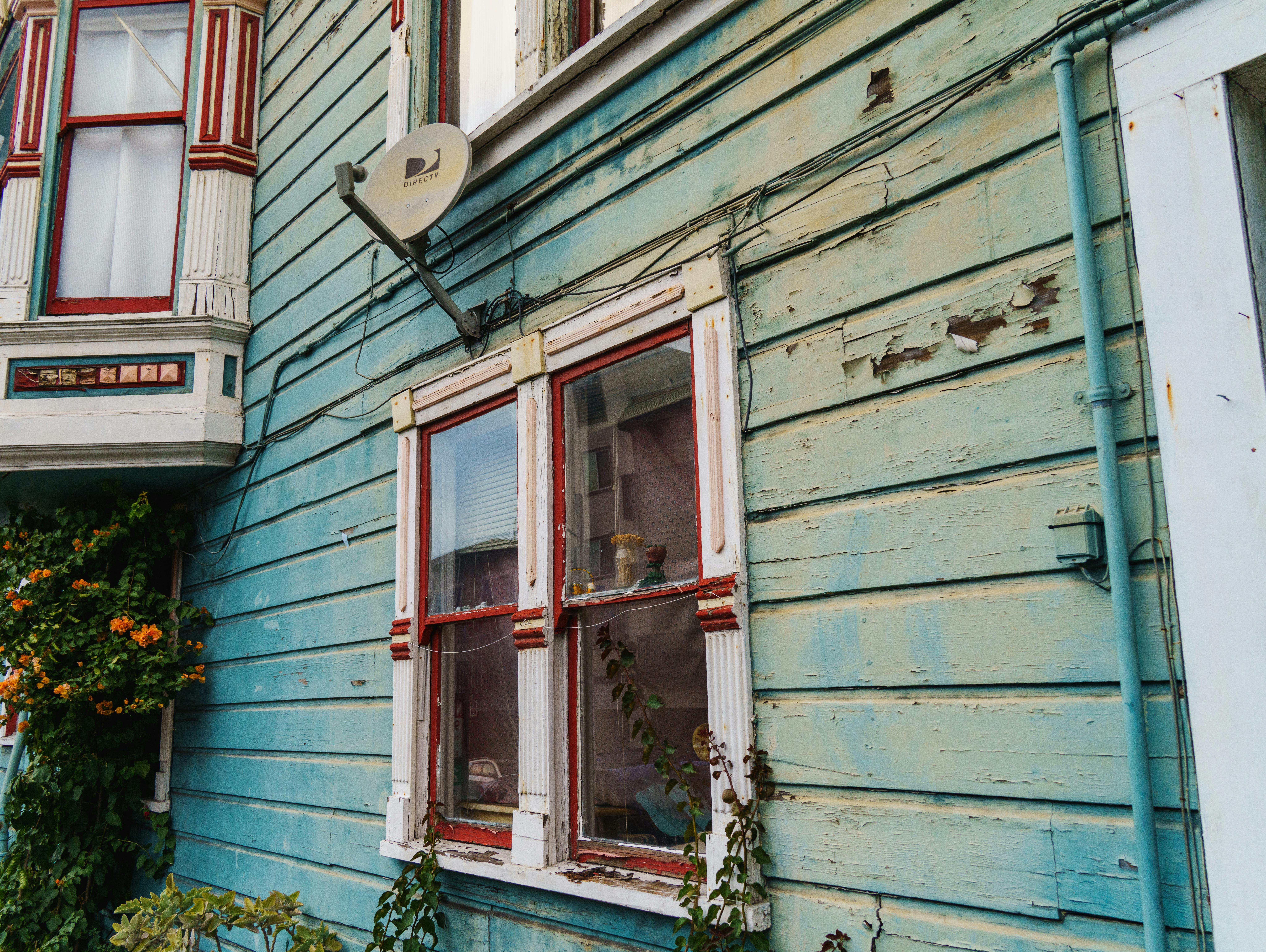 Close-up of a rustic wooden house with aged paint and a satellite dish.