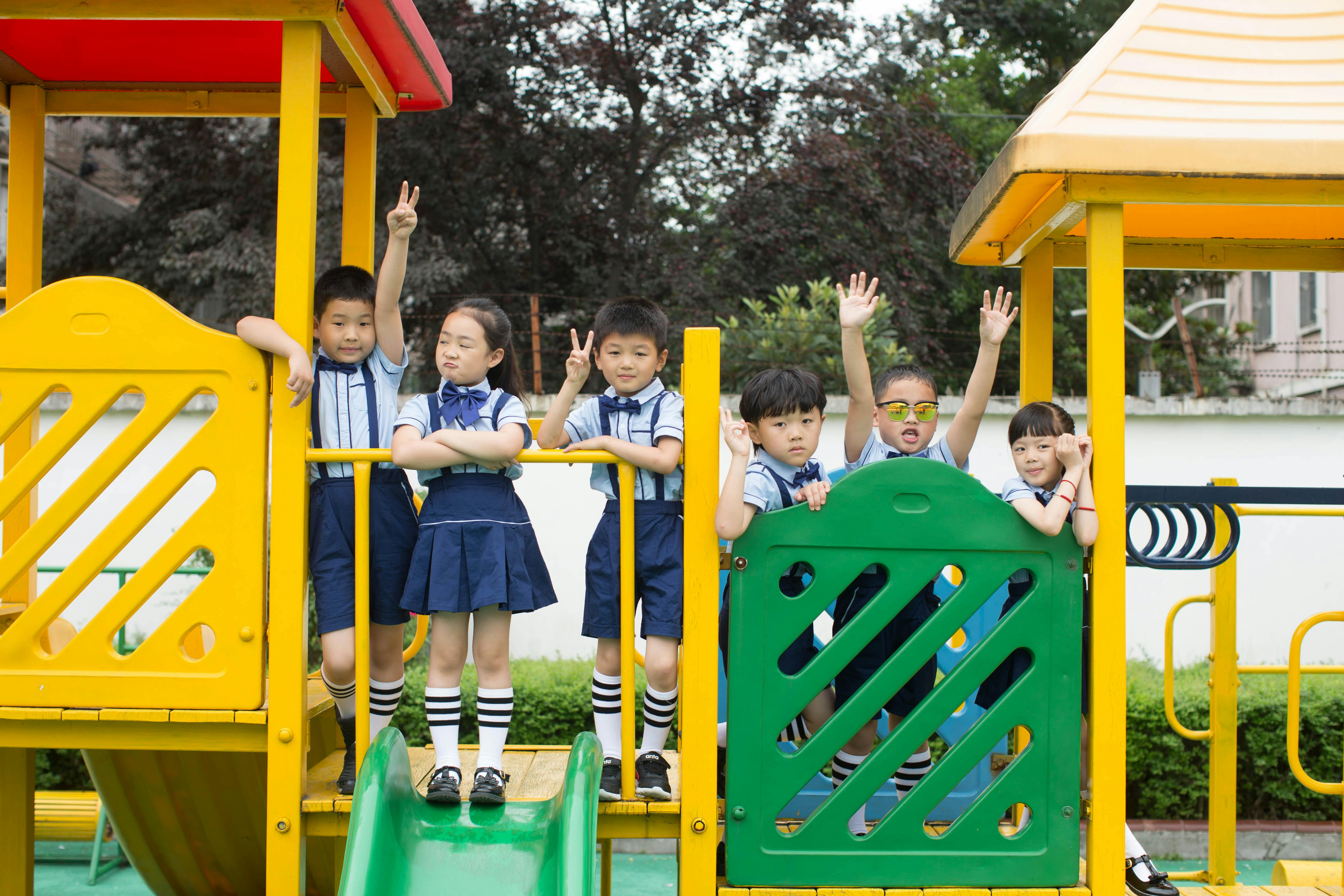 Group of children in uniforms enjoying a sunny day at the playground, showing joy and friendship.