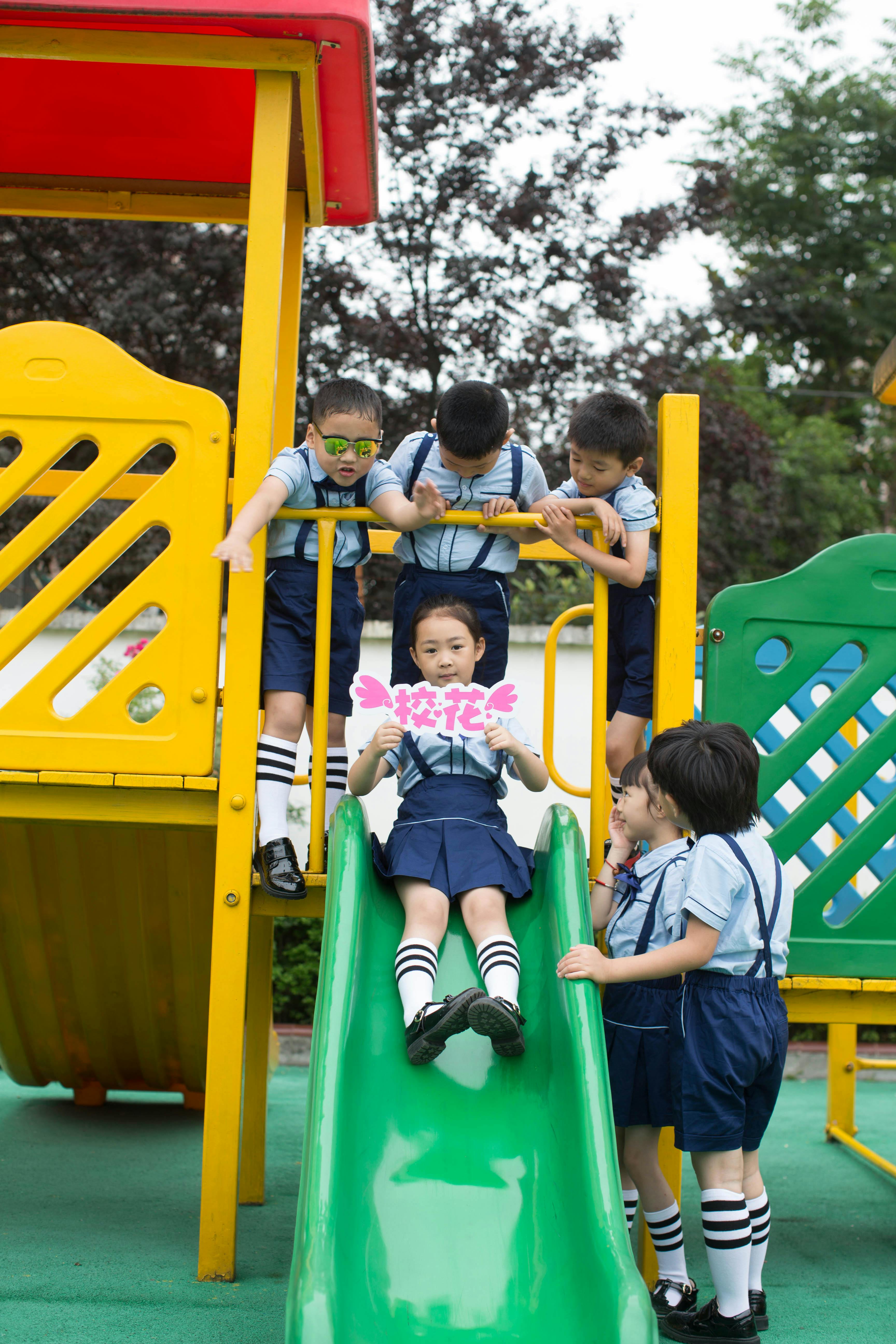 Group of children enjoying playtime on a colorful playground slide outdoors.