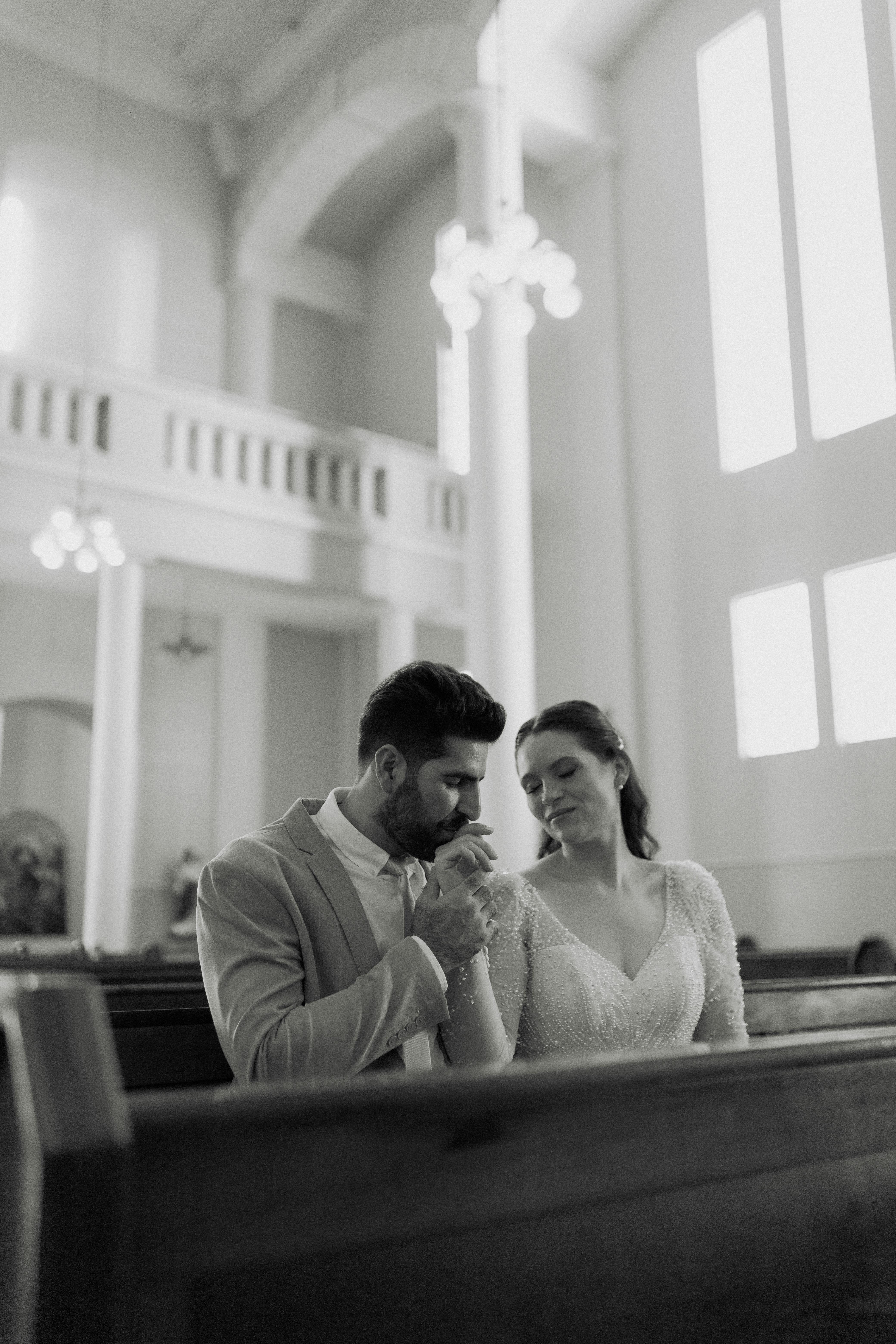Black and white photo of a couple sharing a tender moment inside a church.