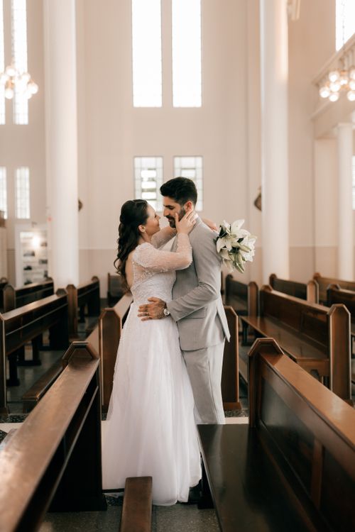 Free Bride and groom embracing in a beautifully lit church interior, capturing love and elegance. Stock Photo