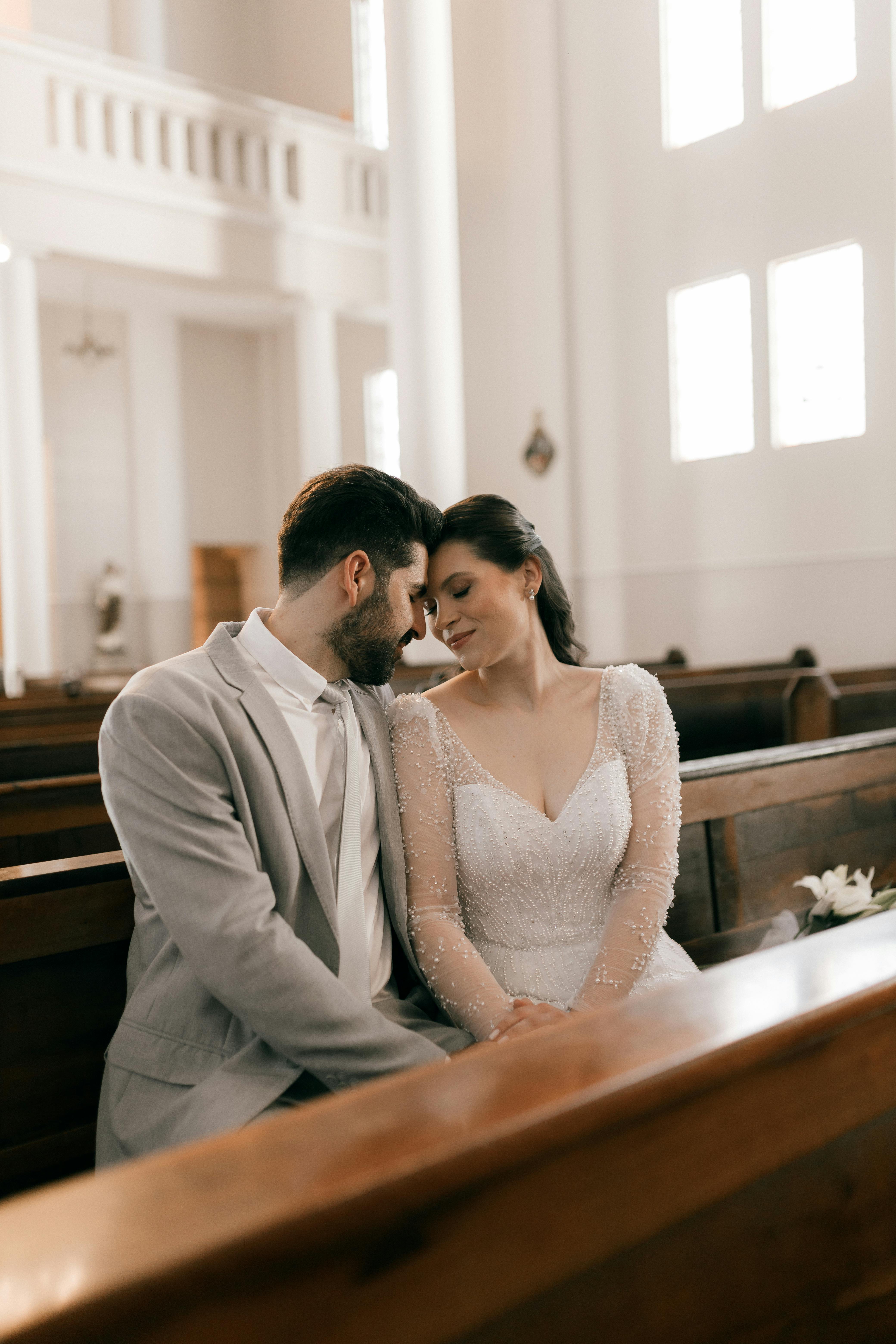 Bride and groom sharing a tender moment in a beautifully lit church.