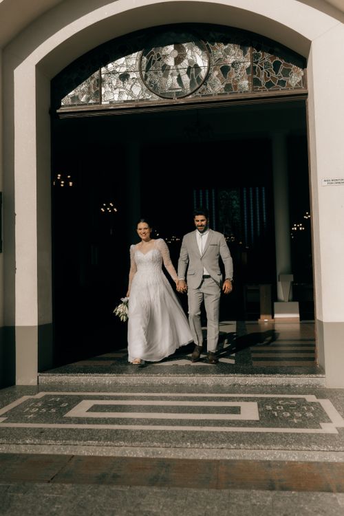 Free Bride and groom leaving church after wedding ceremony, holding hands in sunlight. Stock Photo
