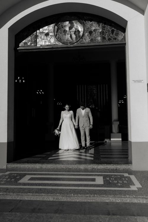 Free A bride and groom in wedding attire leaving a church, captured in monochrome. Stock Photo