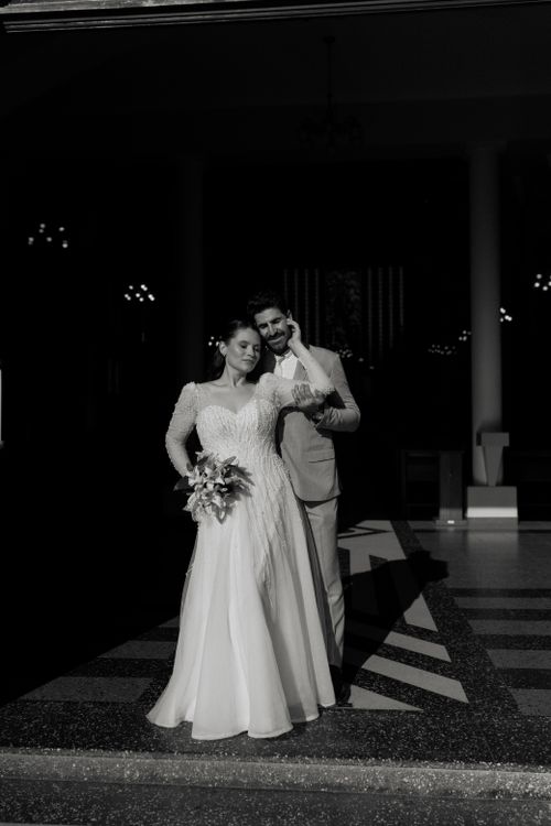 Free A sophisticated black and white wedding portrait of a couple embracing in a formal setting. Stock Photo