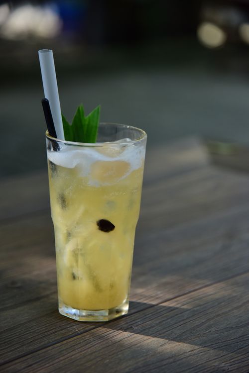 Free Chilled pineapple cocktail with ice, mint, and straw on a wooden surface outdoors. Stock Photo