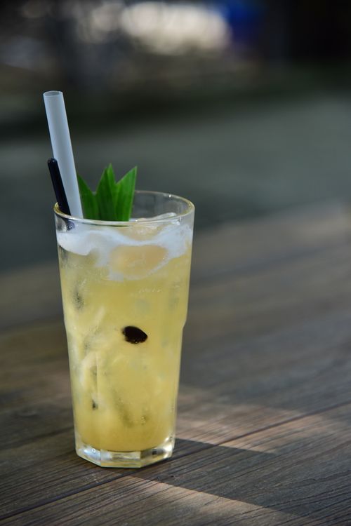 Free Lemon iced cocktail with garnish on a wooden table outdoors in daylight. Stock Photo