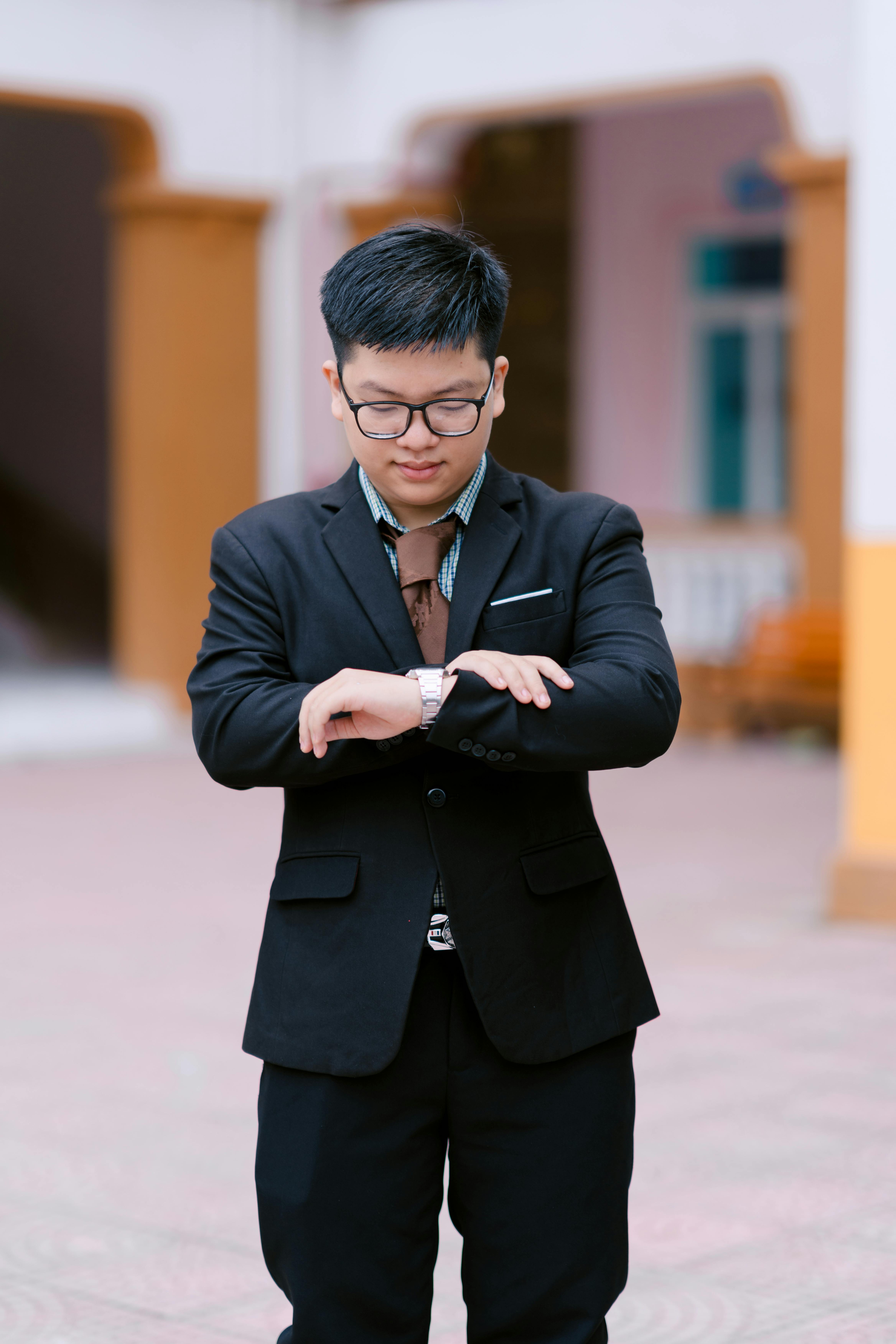 Young man in a suit checks wristwatch outdoors, exuding professionalism.