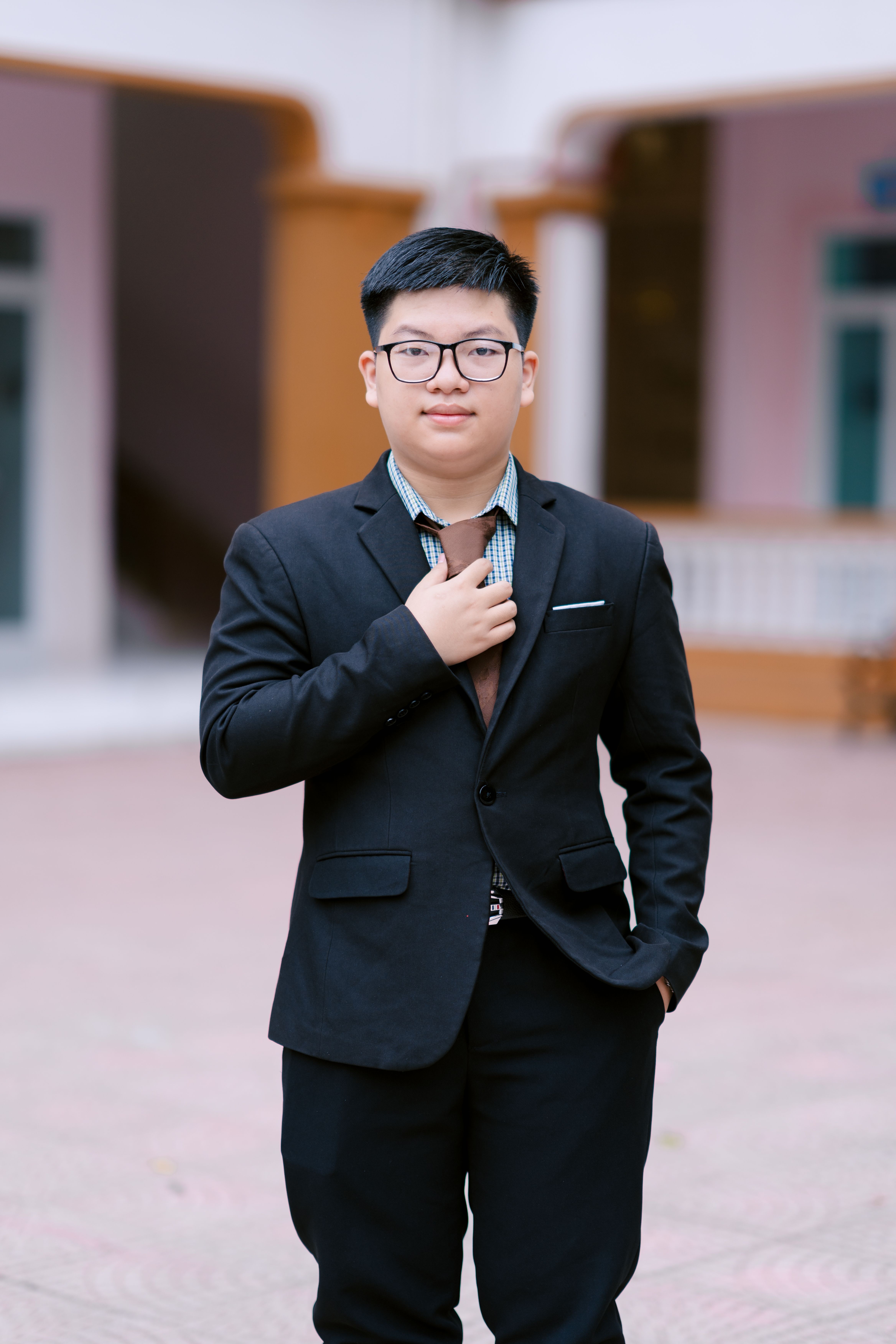 Young adult man in a suit, posing confidently outdoors in an elegant setting.