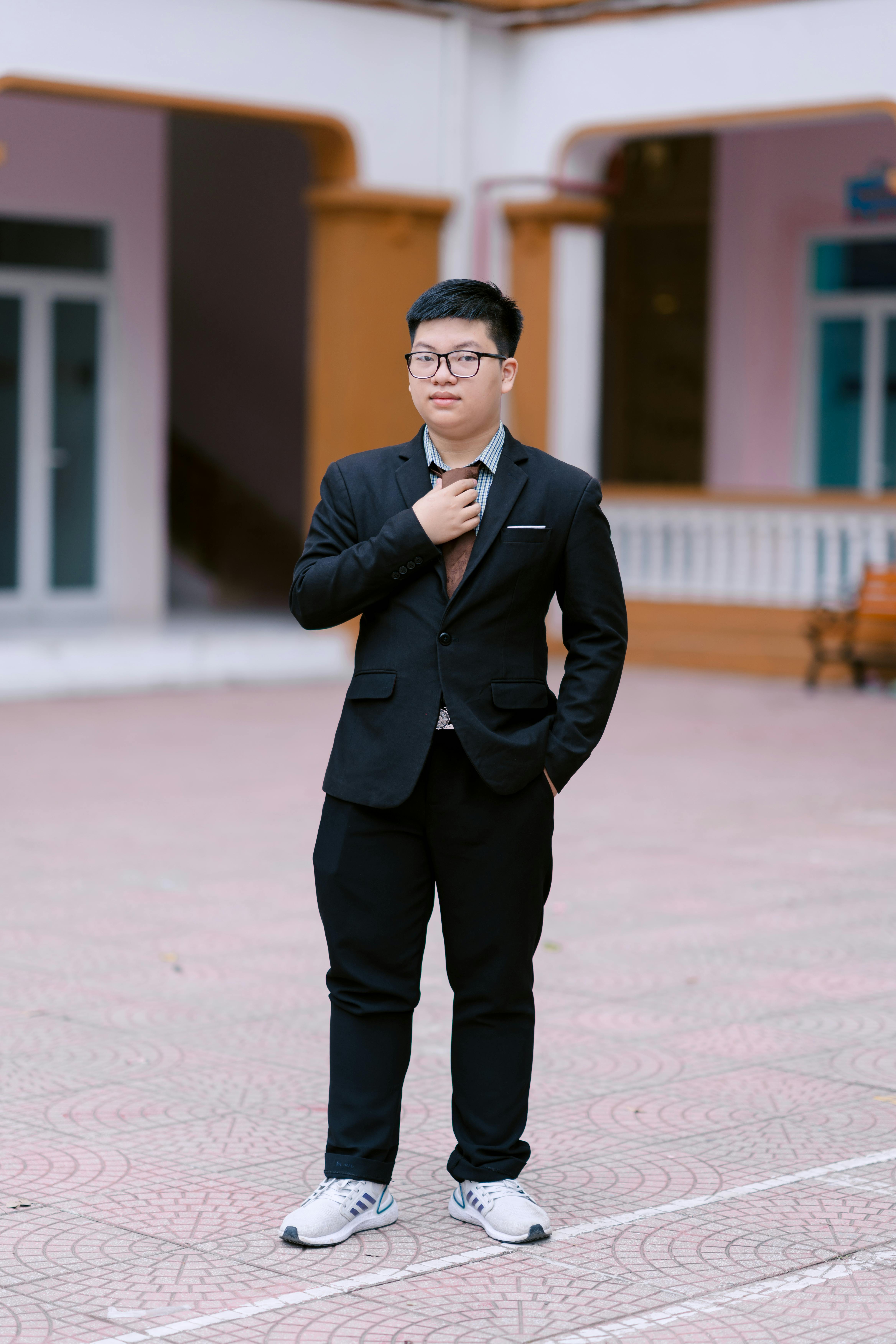 Kostenlos Selbstbewusster junger Mann im Anzug und Turnschuhen posiert im Freien im Innenhof. Stock-Foto