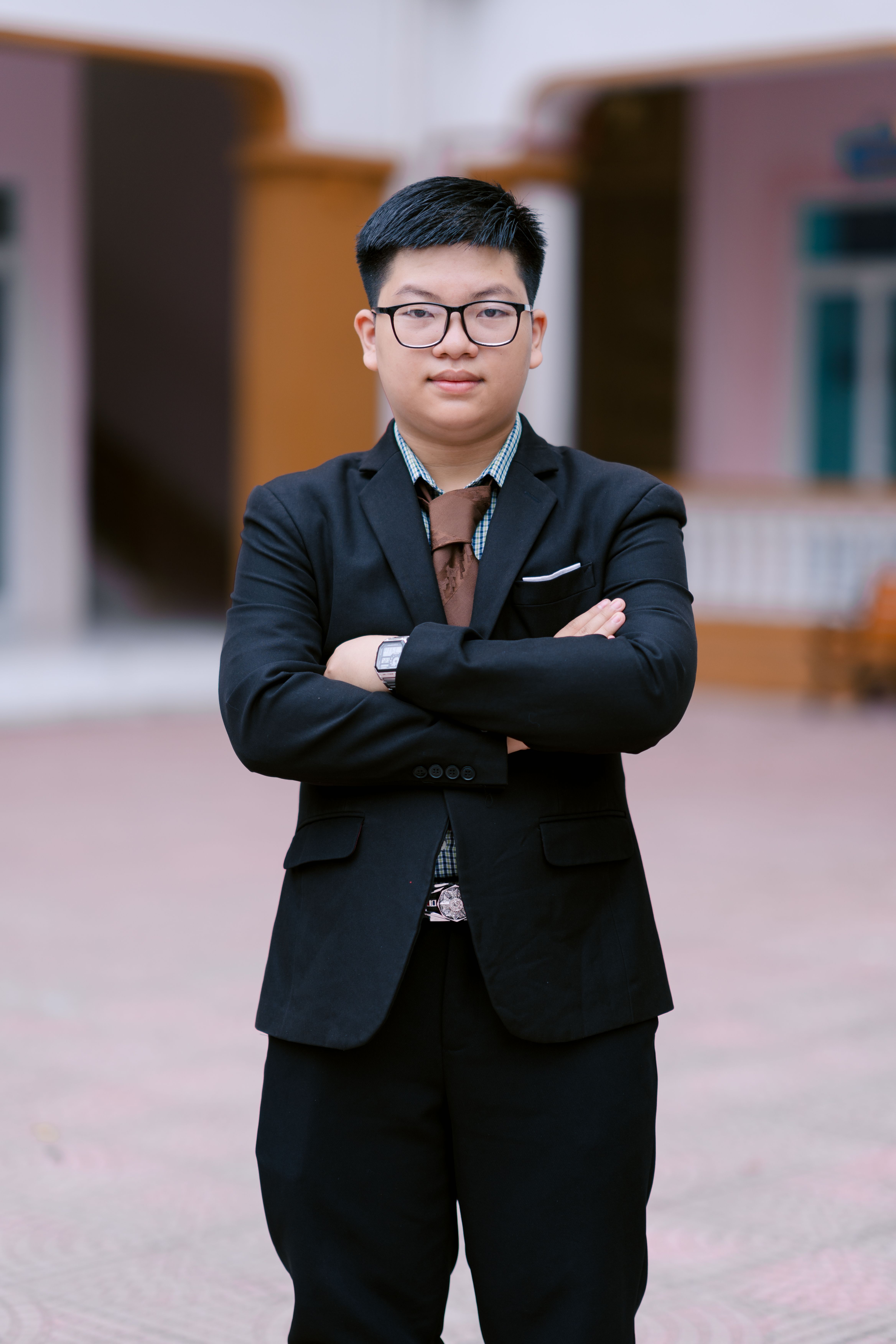 Young businessman in a suit with arms crossed, outdoors, exuding confidence.