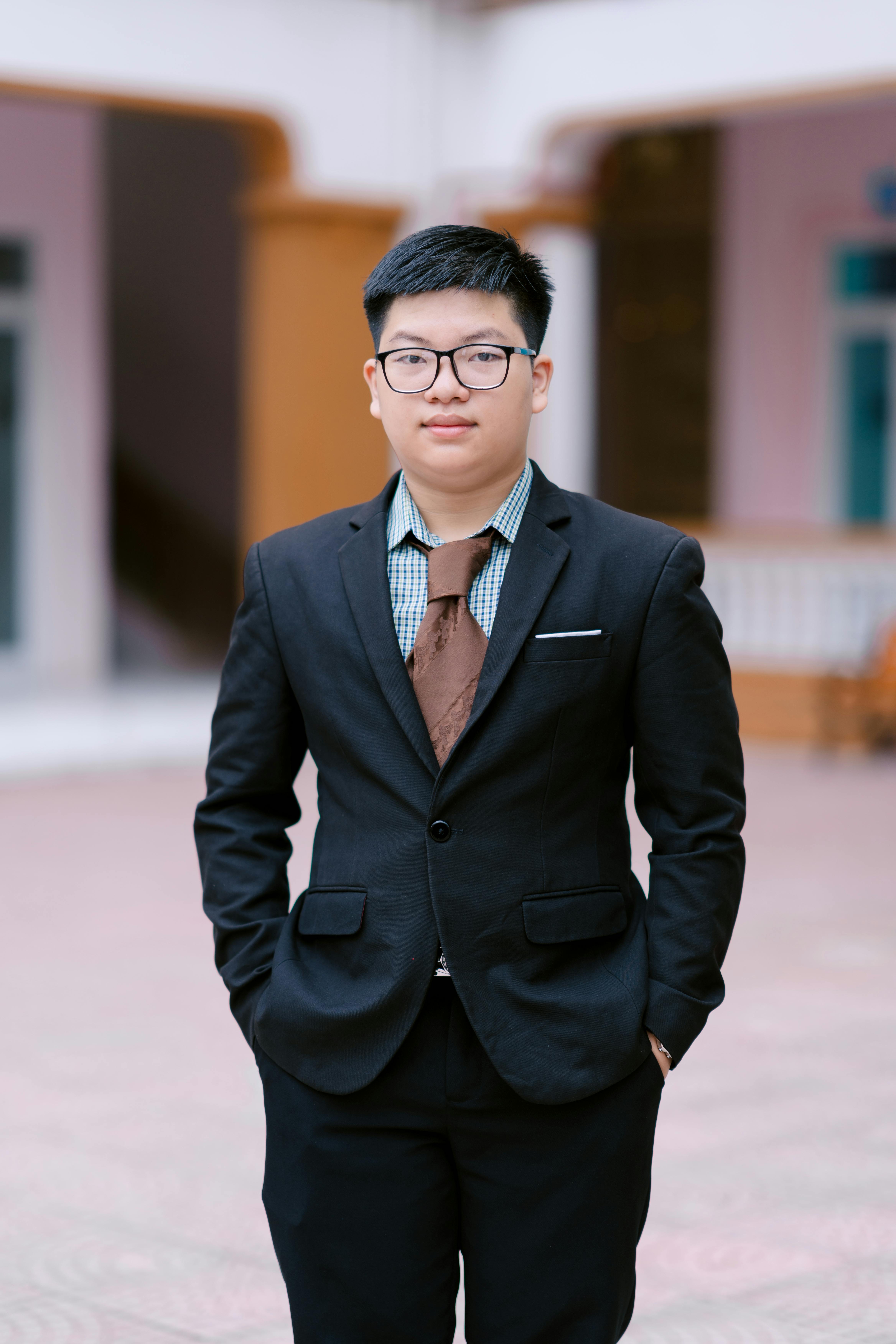 Portrait of a young professional in a suit standing in a courtyard setting.