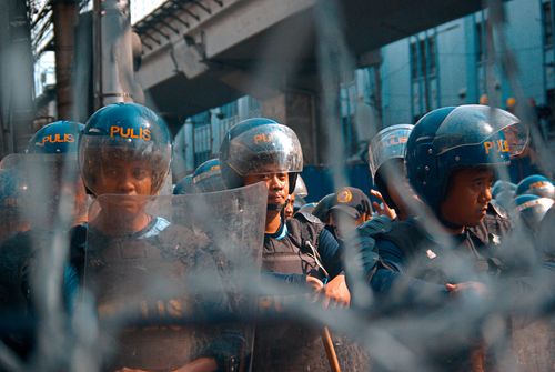 Free Group of police officers in riot gear standing behind shattered glass during a city protest. Stock Photo
