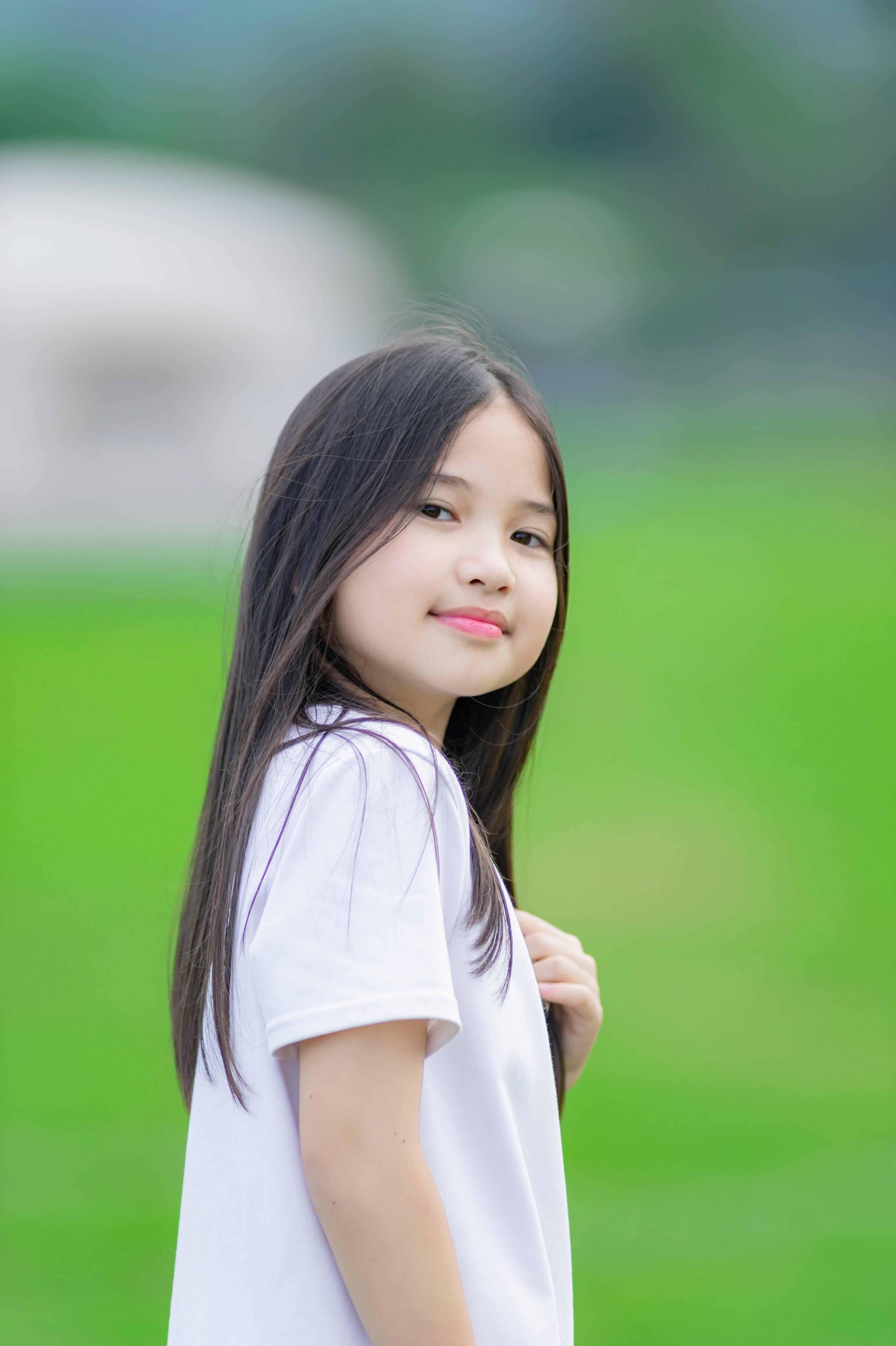 Charming portrait of a young girl with long hair in a green park in Hà Nội, Vietnam.