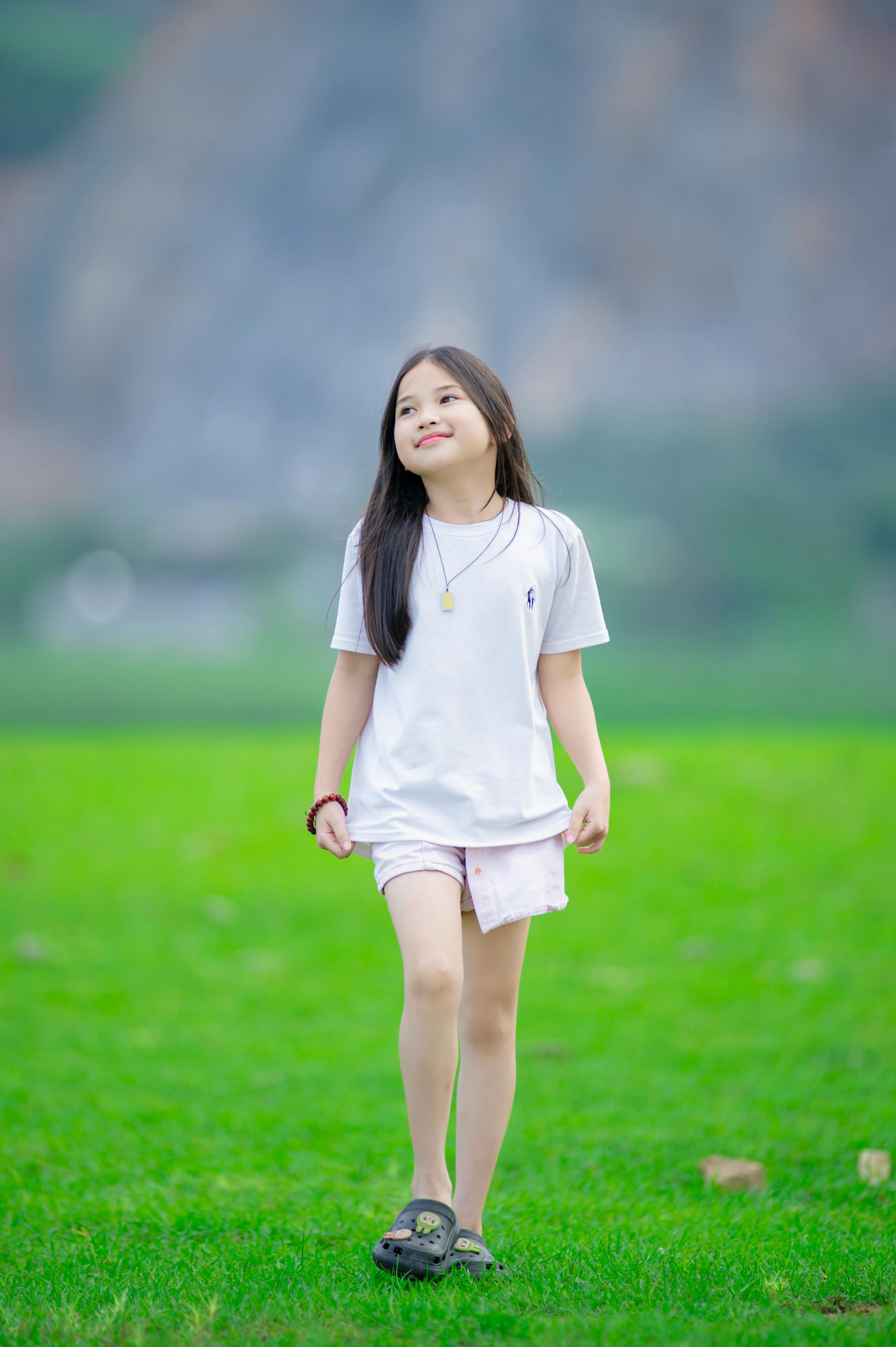 A happy young girl strolling on a green lawn in Hanoi, Vietnam.