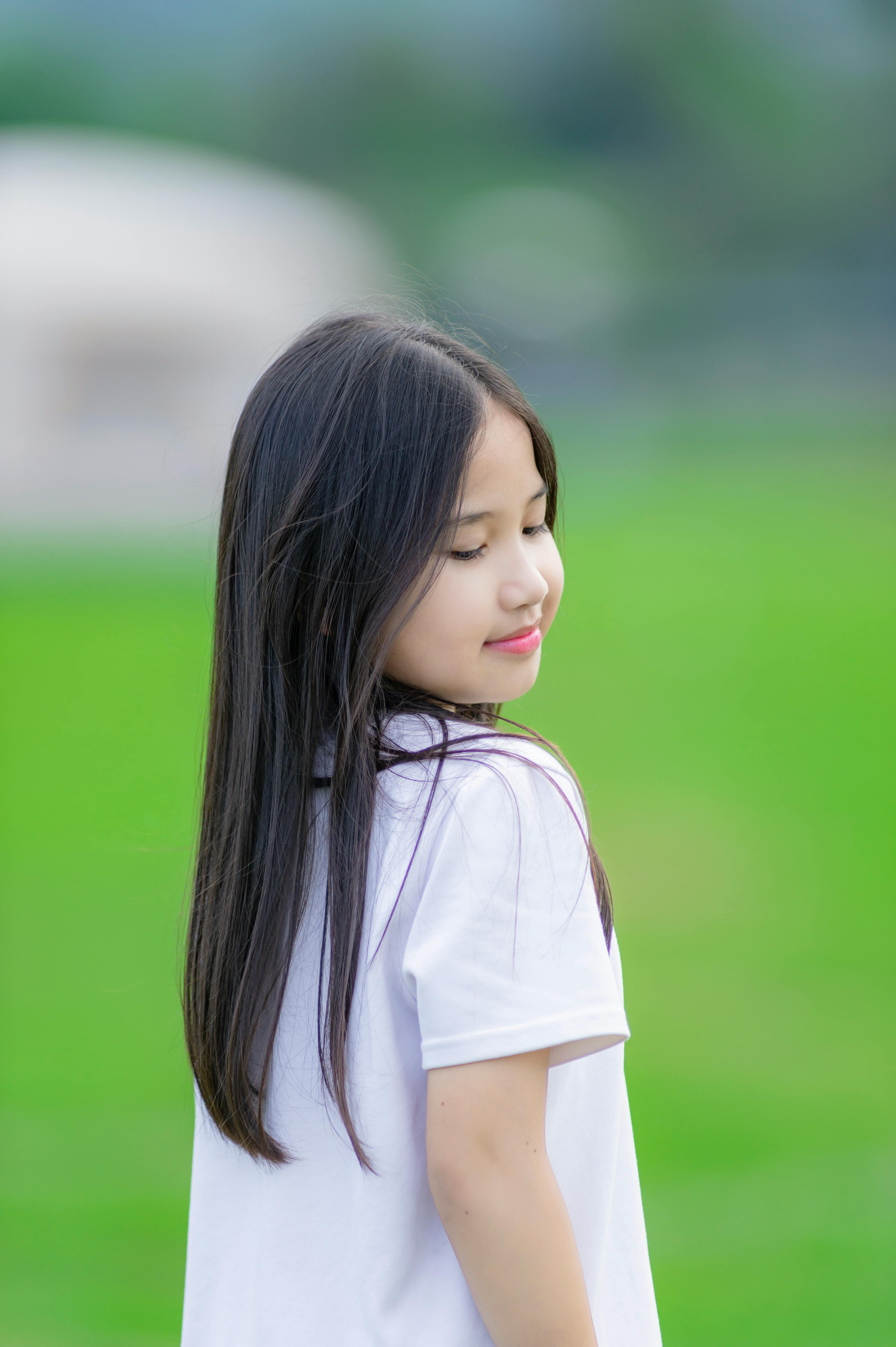 Gratis Gadis muda yang menggemaskan dengan rambut hitam panjang di luar ruangan, Hanoi. Momen damai dan tenteram tertangkap. Foto Stok