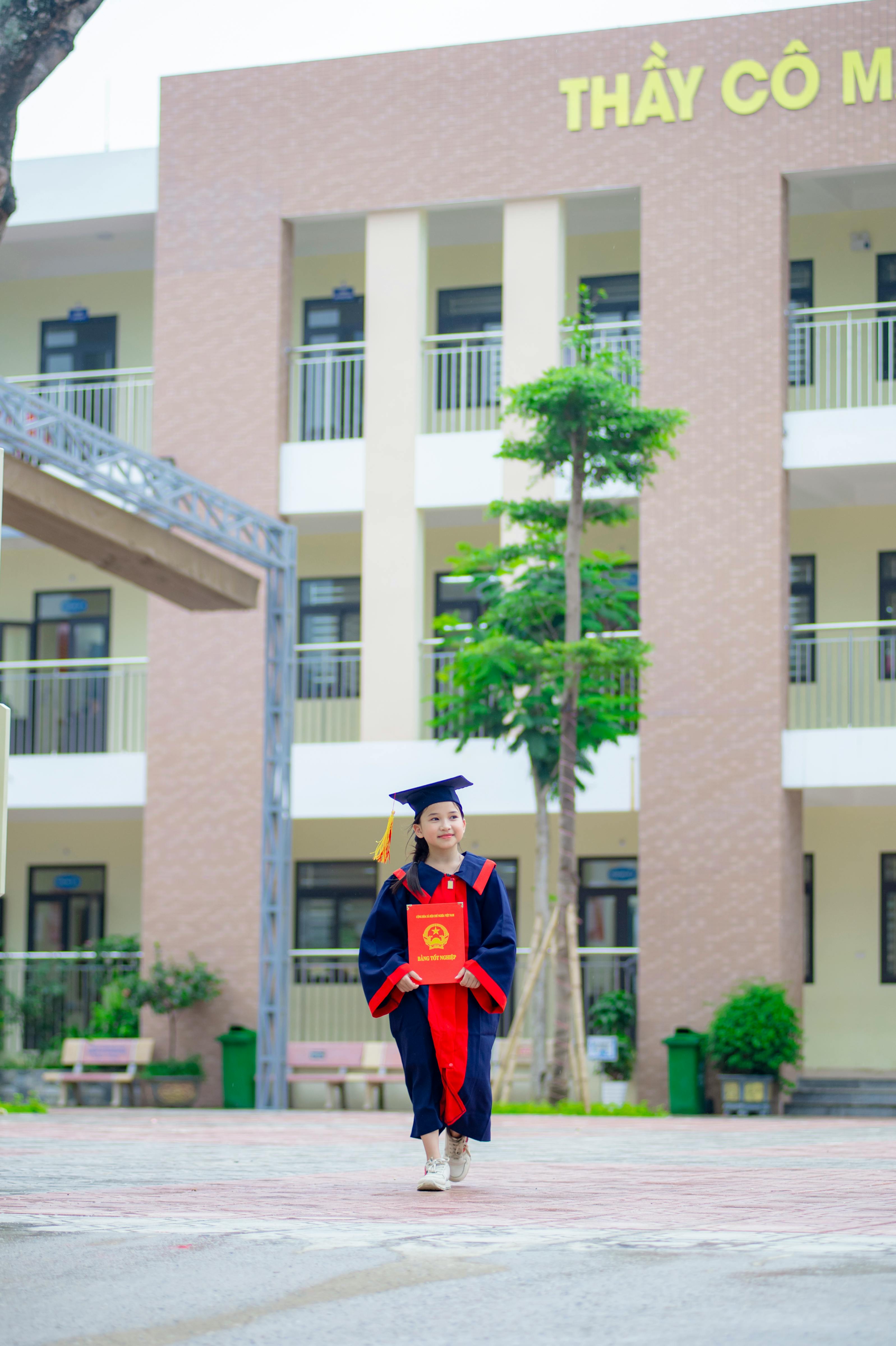 gratis Een jonge afgestudeerde poseert trots in toga en baret op een school in Hanoi, Vietnam. Stockfoto