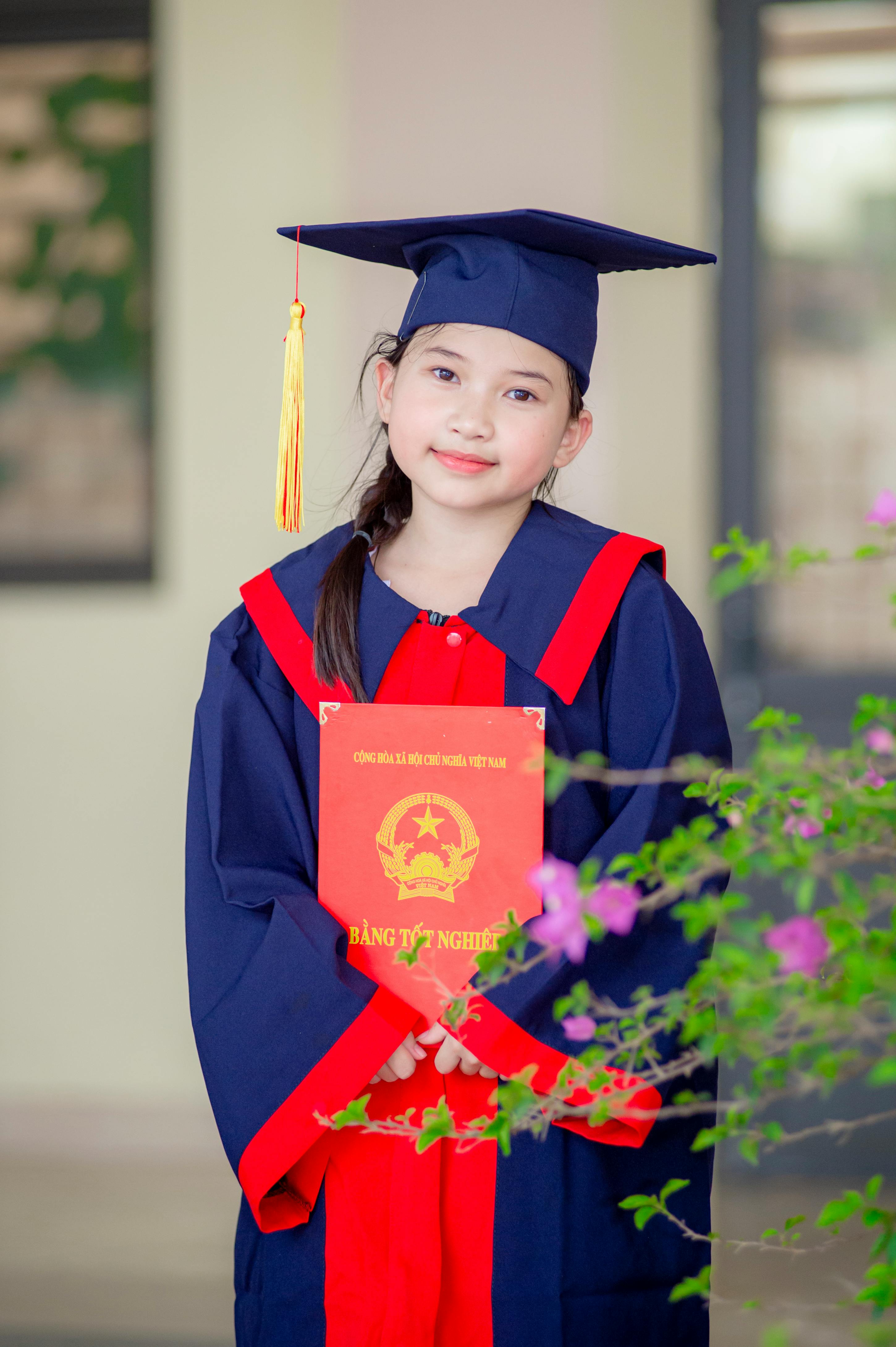 Gratuit O tânără fată în ținută de absolvire își ține cu mândrie diploma în Hà Nội, Vietnam. Fotografie de stoc