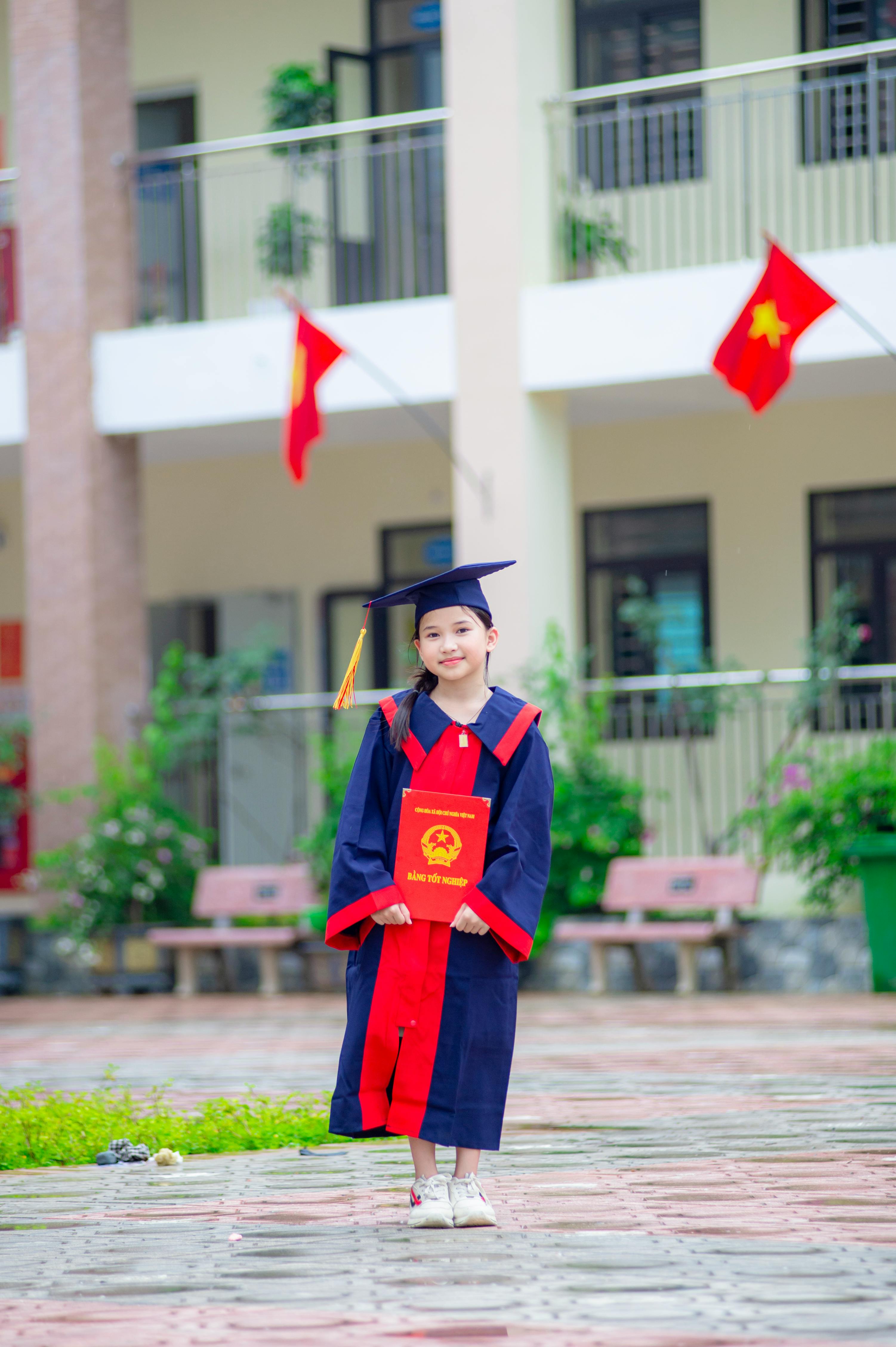 Ücretsiz Vietnam'ın Hanoi kentinde mezuniyet kıyafeti giymiş genç kız, açık havada sertifikasını tutuyor. Stok Fotoğraflar