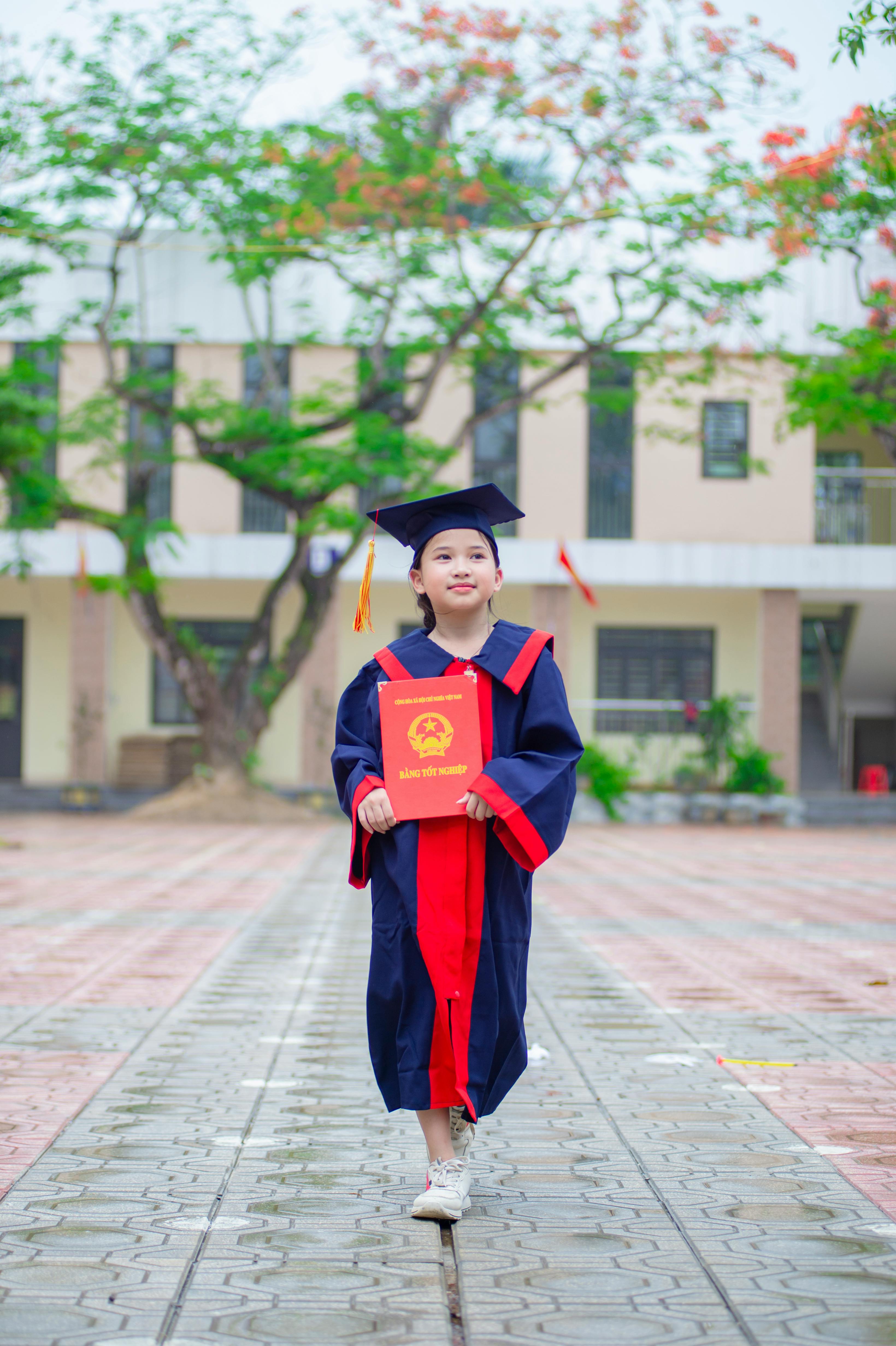 gratis Een trots jong meisje in afstudeerkleding poseert buiten met haar certificaat. Stockfoto