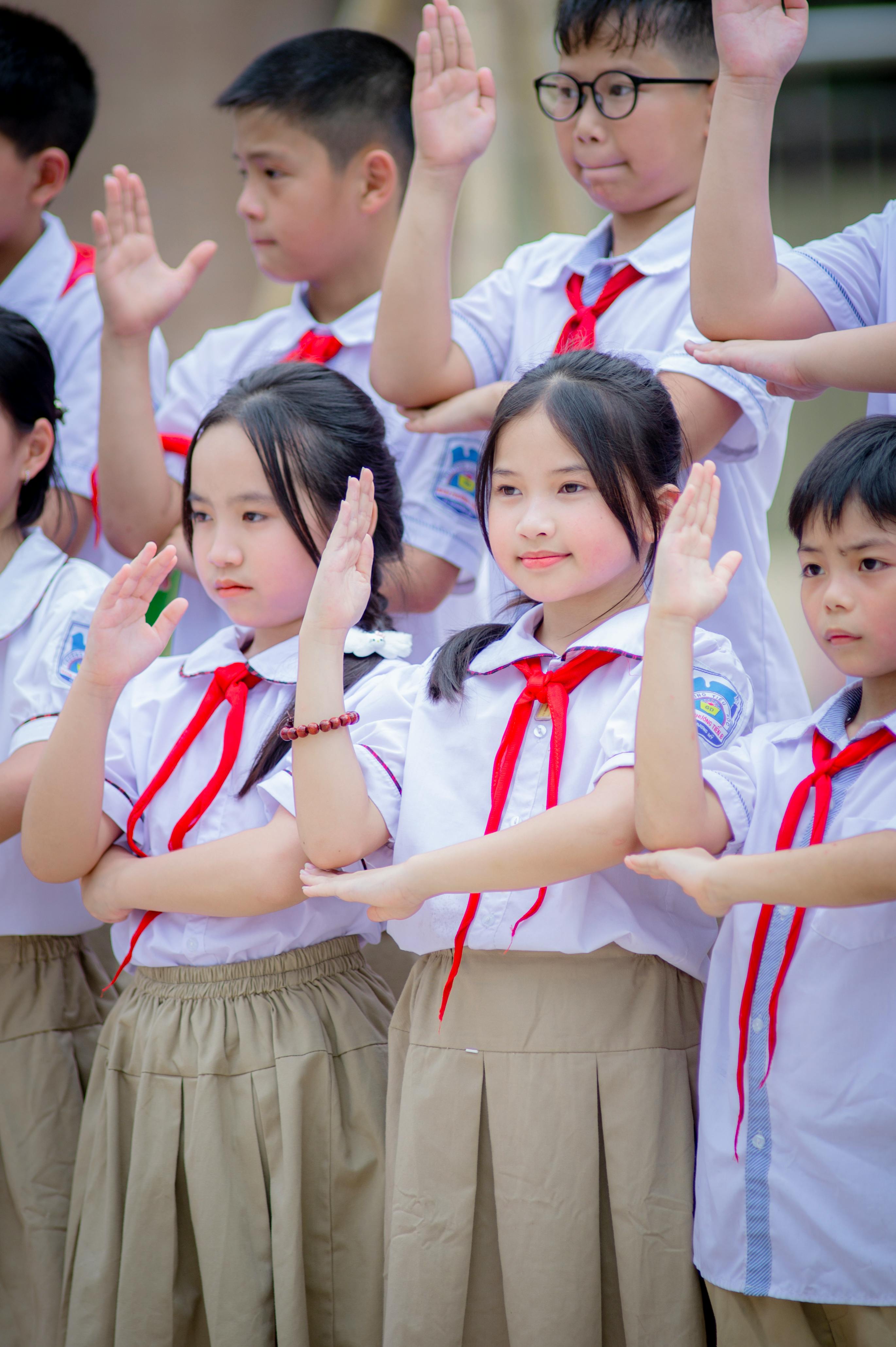 Gratis Grupo de escolares vietnamitas uniformados realizando un saludo al aire libre en Hanoi. Foto de stock