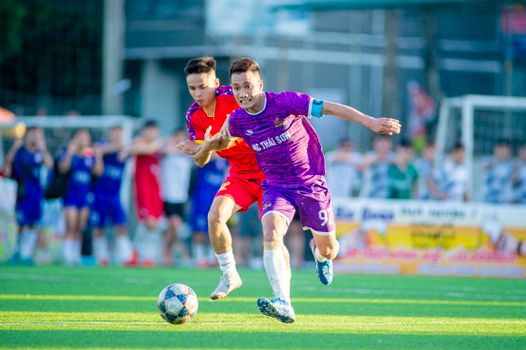 Action-packed football match with players in intense competition on a sunny day in Hanoi, Vietnam.