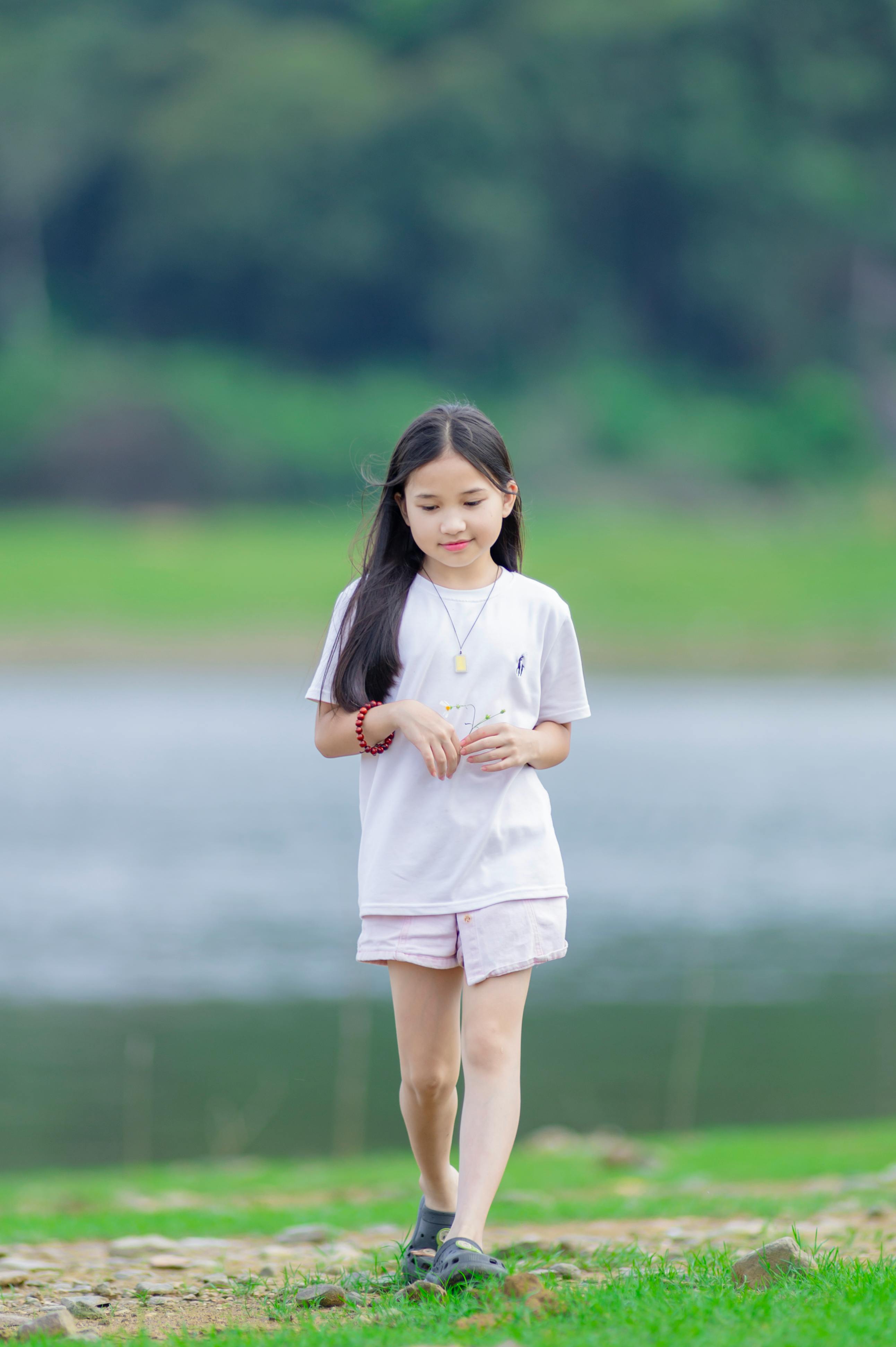 gratis Een sereen portret van een jong meisje dat langs een meer met weelderig groen loopt in Hanoi, Vietnam. Stockfoto