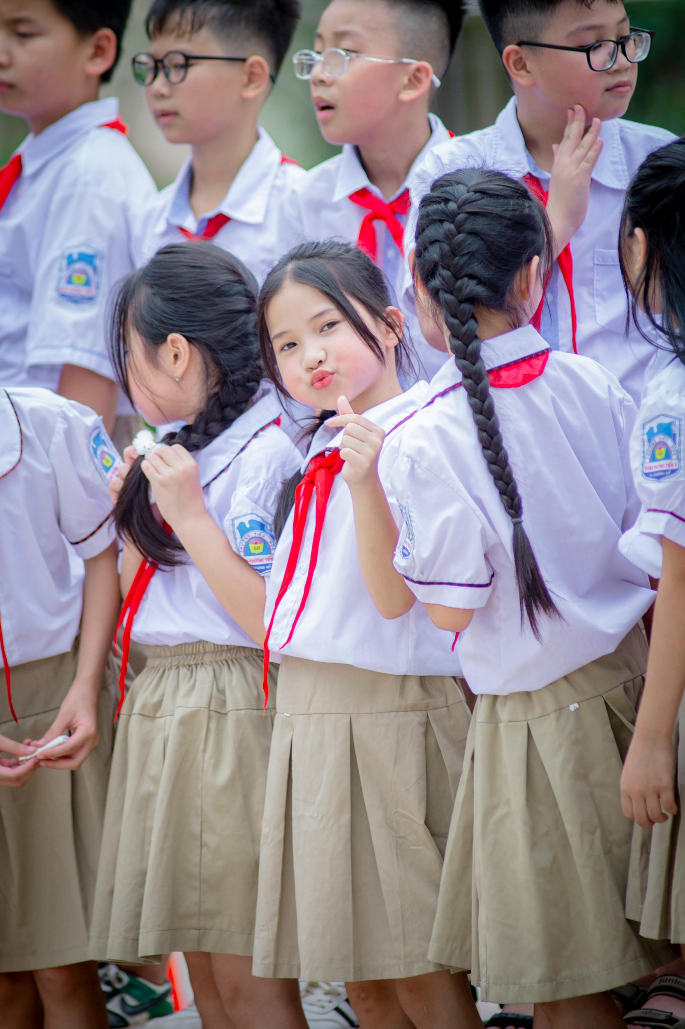 gratis Een groep vrolijke Vietnamese schoolkinderen in uniform staat overdag buiten. Stockfoto