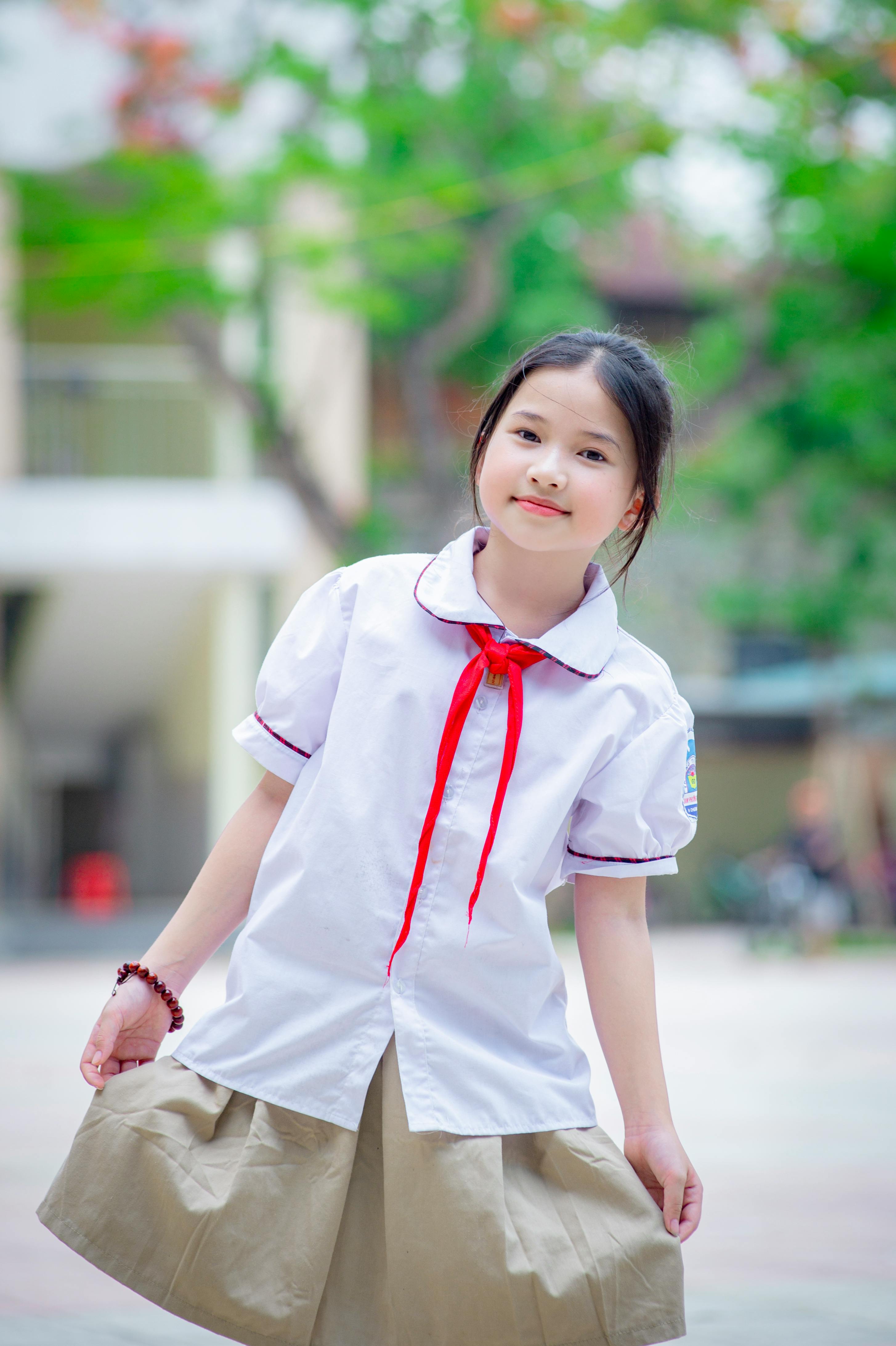 Gratis Gadis muda yang menggemaskan berseragam sekolah tersenyum cerah, diambil di luar ruangan di Hanoi, Vietnam. Foto Stok