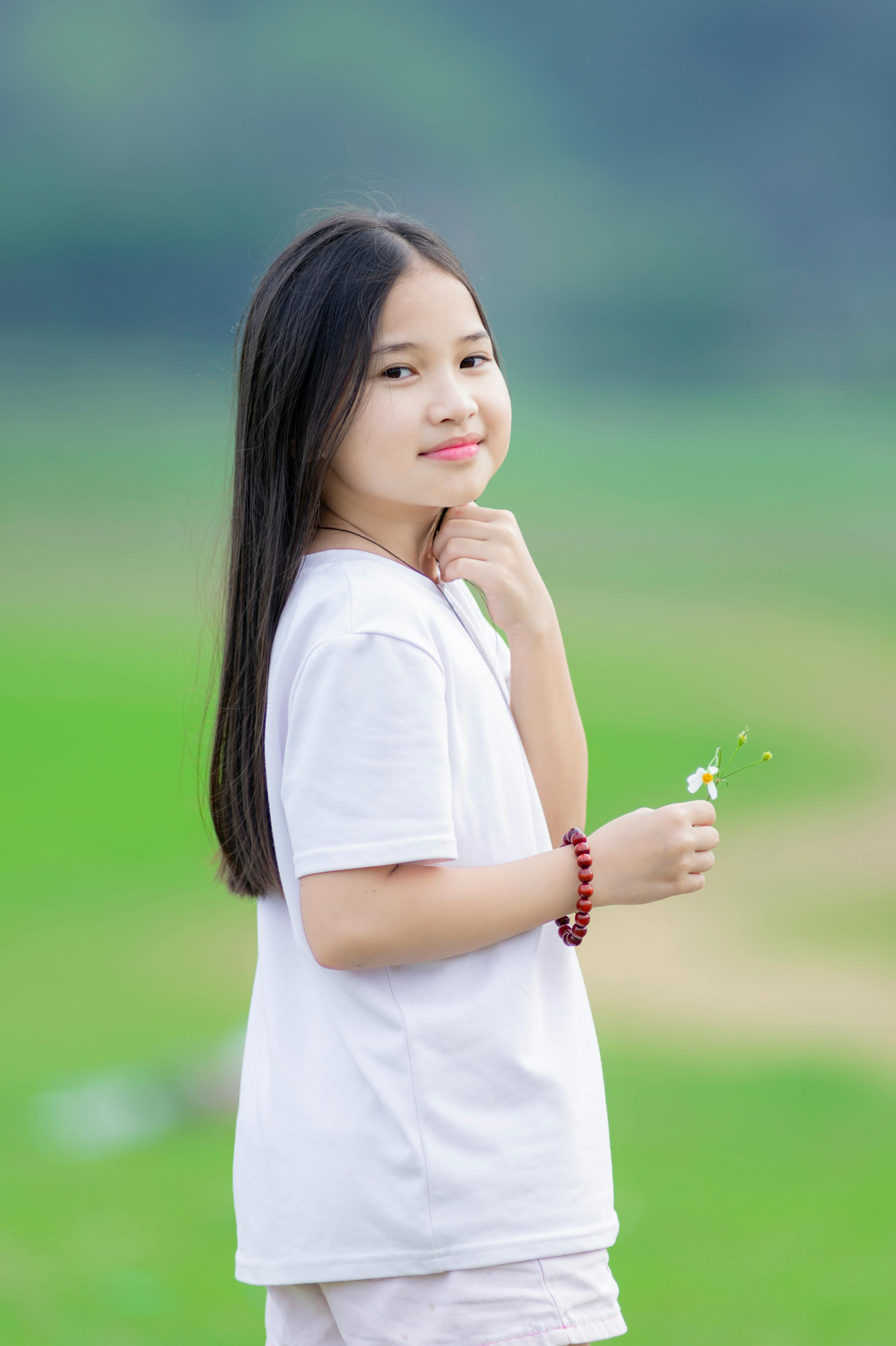 Free Charming portrait of a young girl holding a flower outdoors in Hanoi. Stock Photo