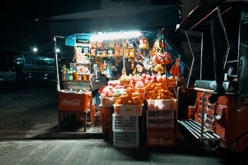 Free A vibrant street vendor selling fresh produce at a night market with colorful lights. Stock Photo