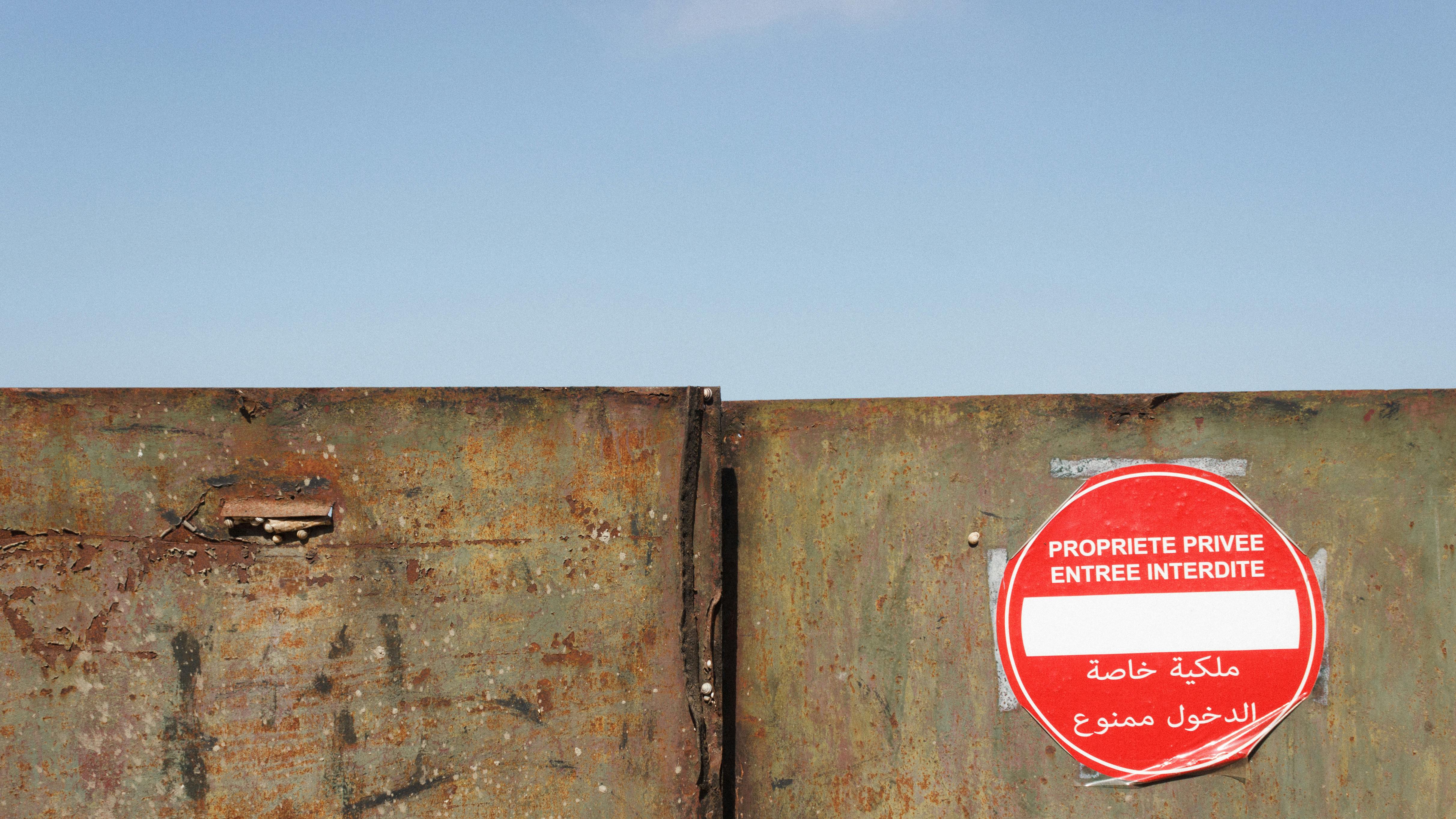 A rusty gate with a private property sign in French, outdoors on a clear day.