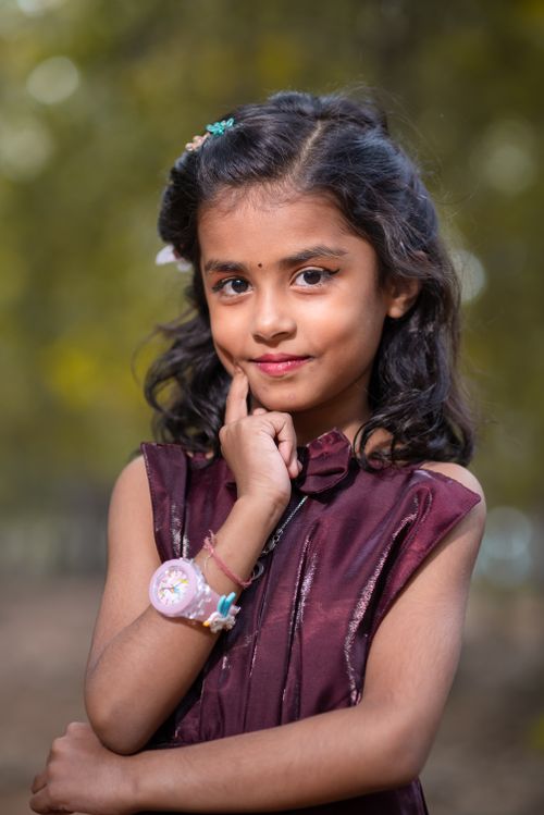 Free Portrait of a young Indian girl smiling in an outdoor setting, wearing a magenta dress. Stock Photo