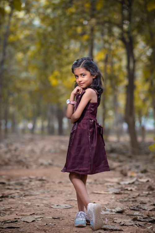 Free Cute young girl posing confidently in a serene forest path, showcasing innocence and charm. Stock Photo