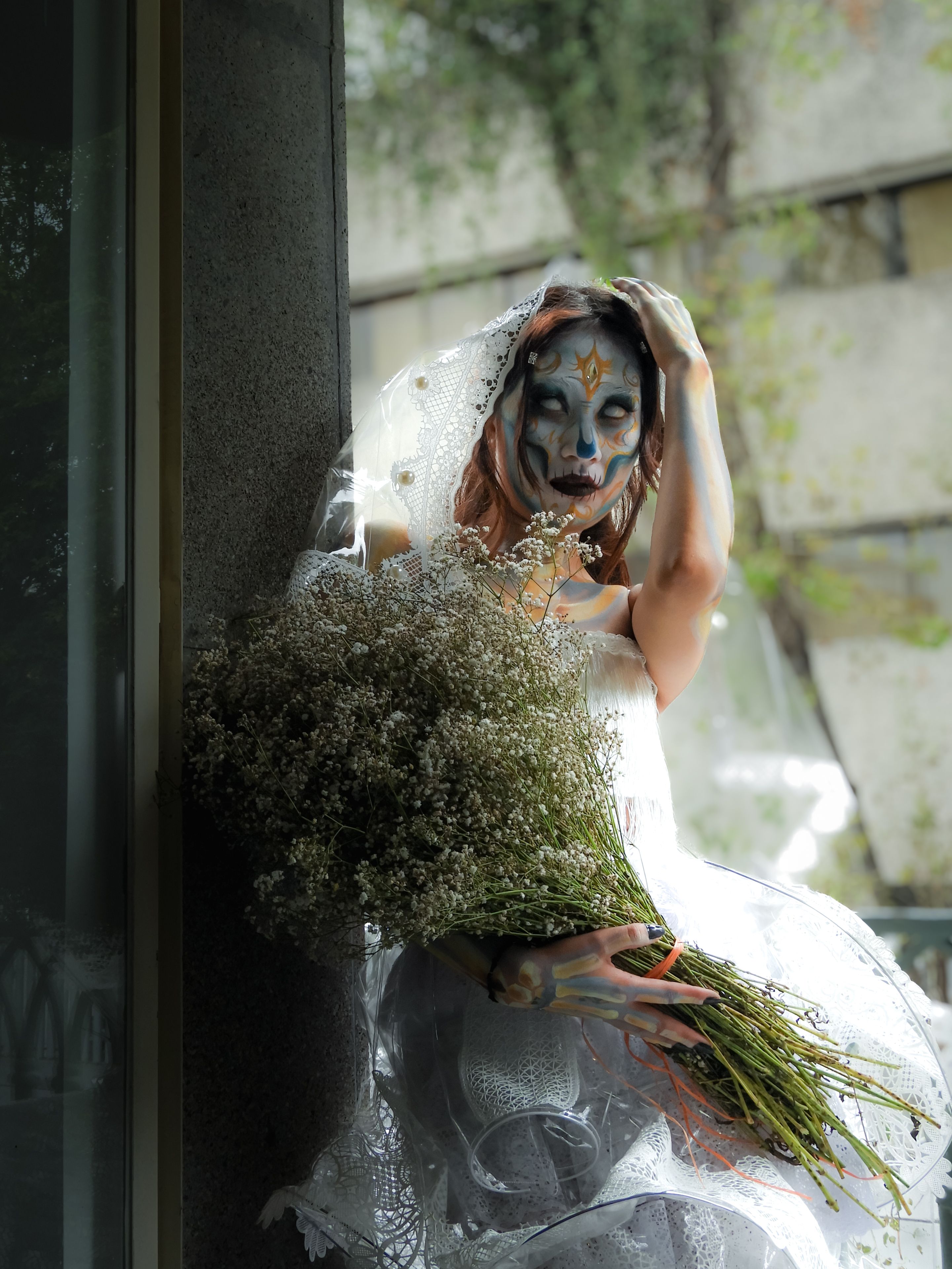 Creative Day of the Dead costume featuring a masked bride holding a large bouquet indoors.