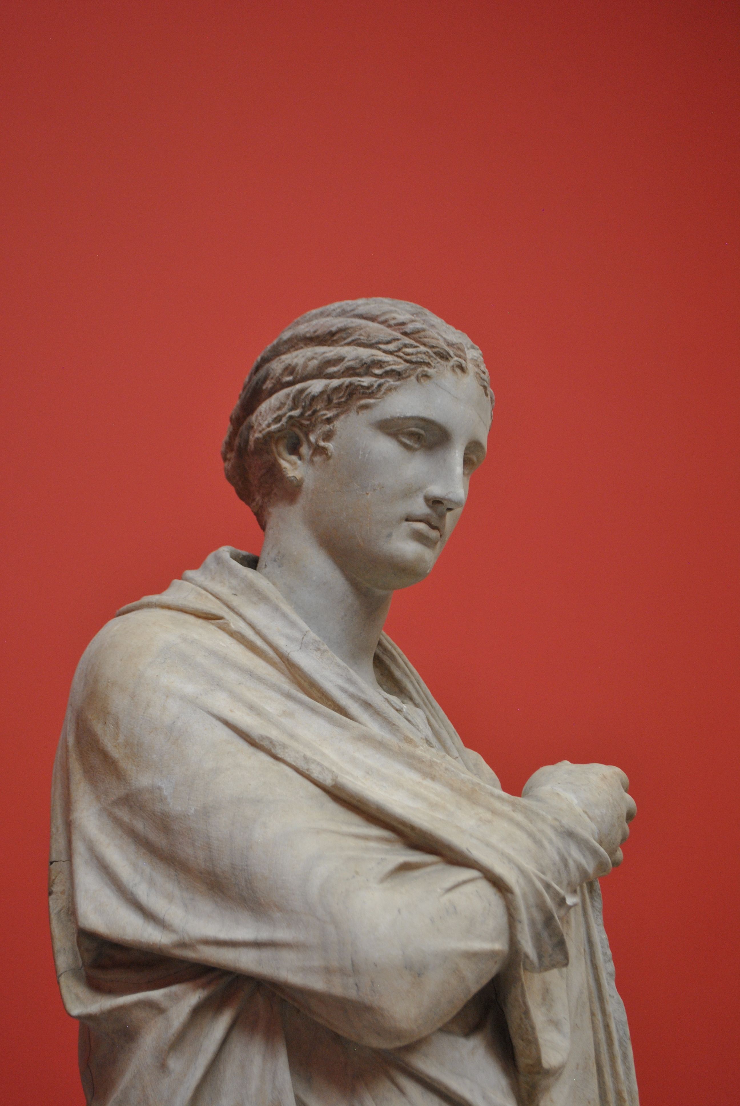 Elegant marble statue depicting classical art against a vibrant red backdrop.