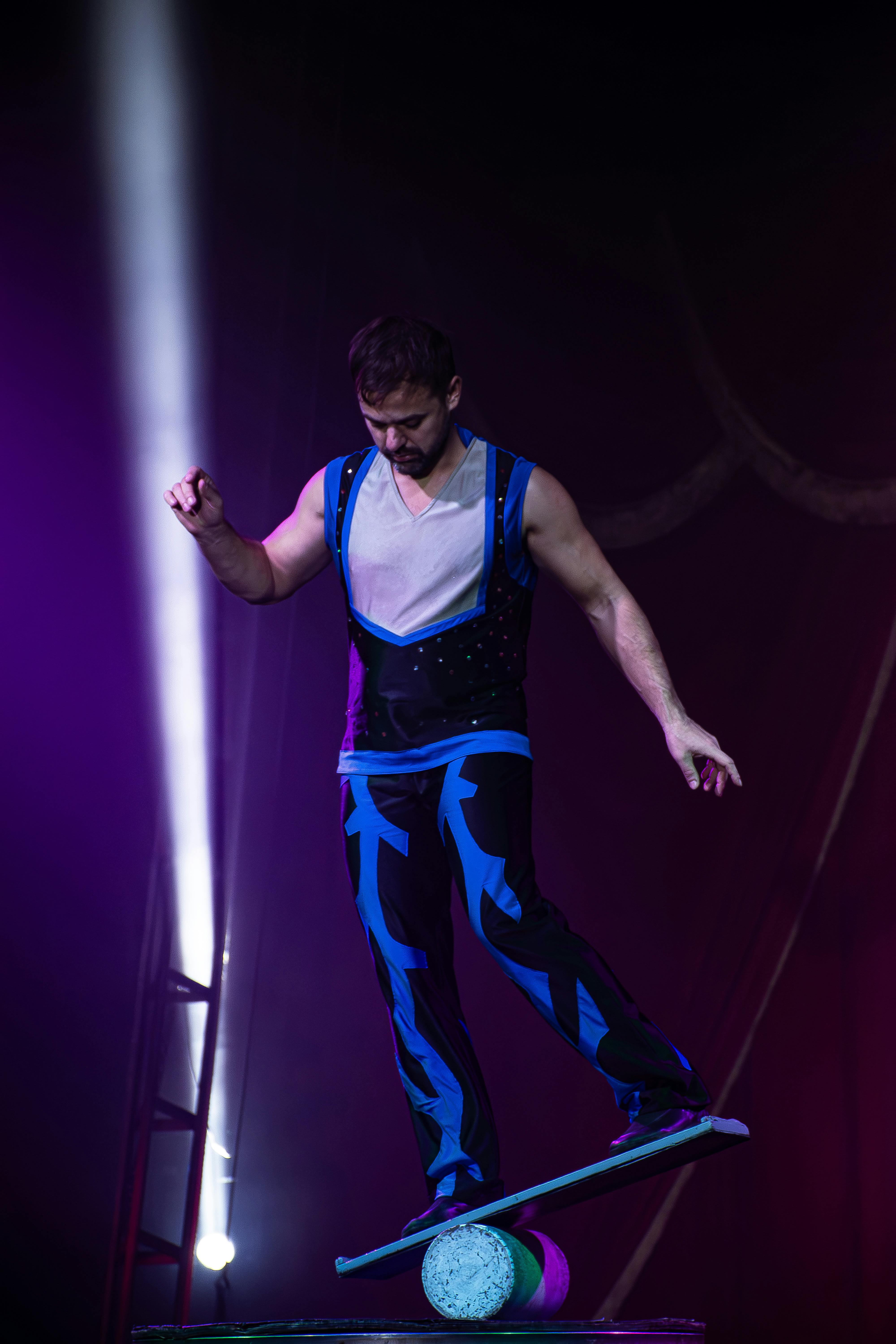 A skilled performer executes a balance act on a circus stage, showcasing dexterity.