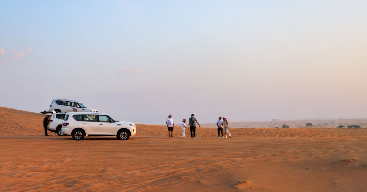 Tourists explore the desert landscape with off-road vehicles under a warm sky.